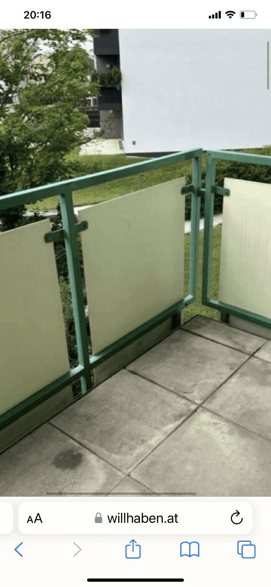 Balkon mit grüner Brüstung und Betonplattenboden, umgeben von Bäumen und Grünflächen.