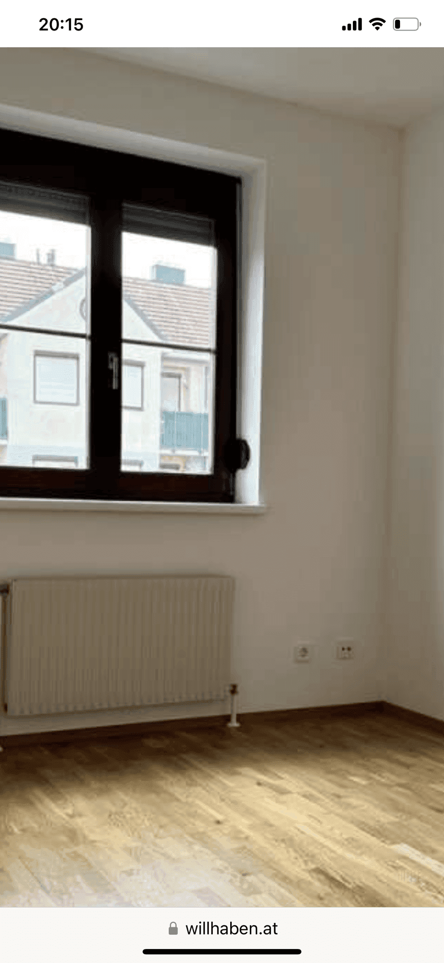 Nahaufnahme eines Fensters mit Heizkörper und hellem Parkettboden in einem Innenraum.