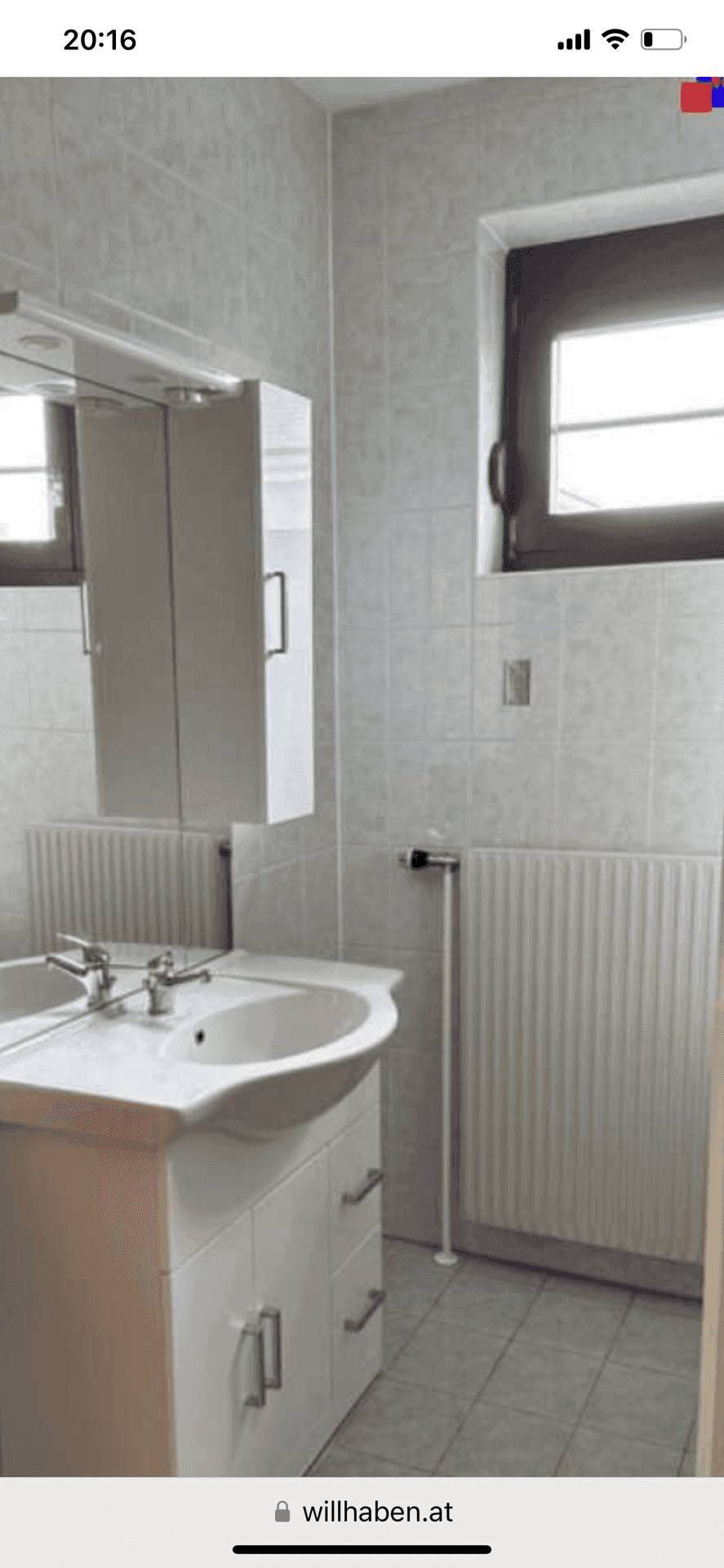 Badezimmer mit Waschbecken, Spiegelschrank und Fenster, gefliest in hellen Farbtönen.
