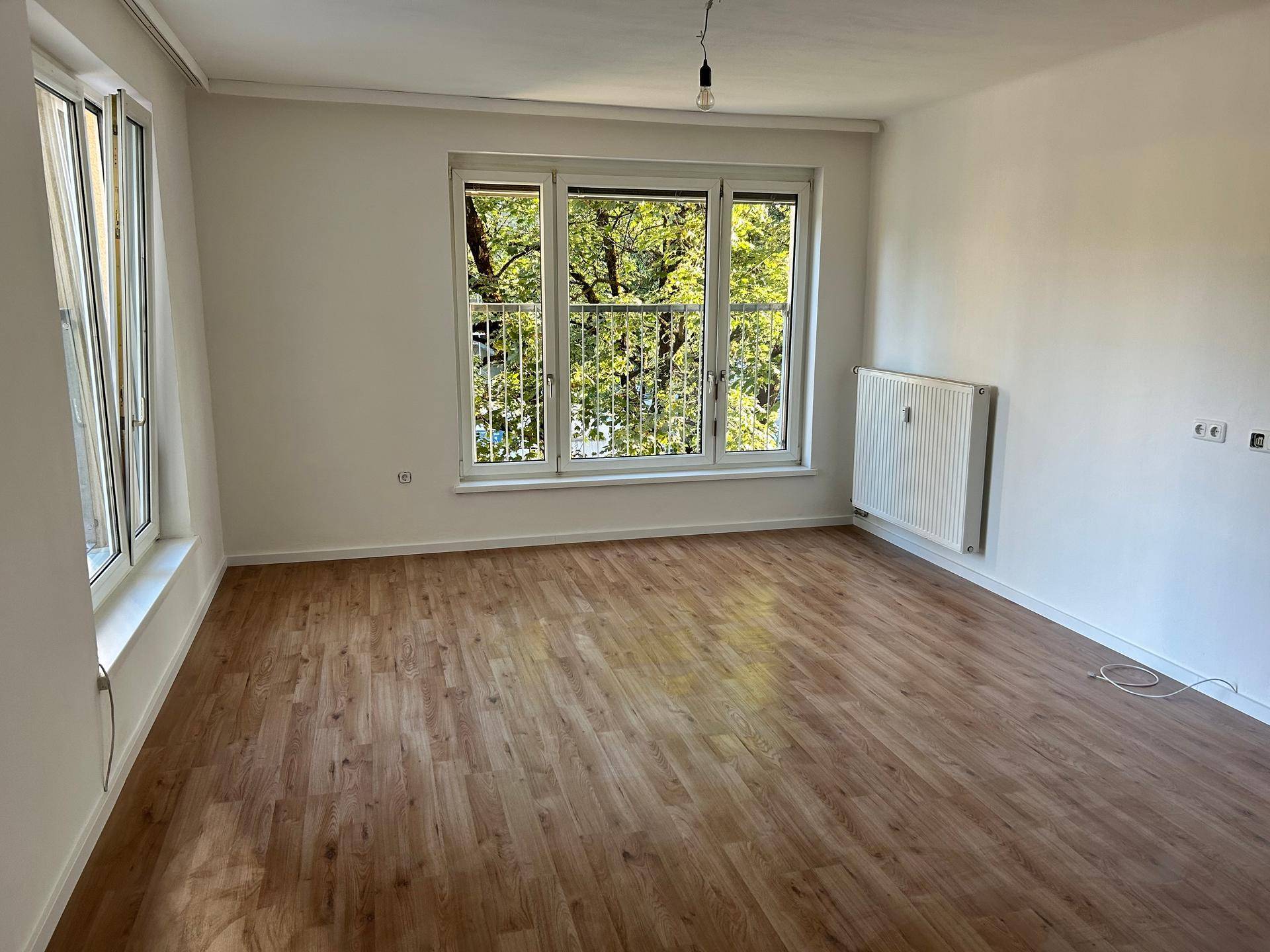 Helles und geräumiges Zimmer mit zwei Fenstern, Laminatboden und Blick ins Grüne.