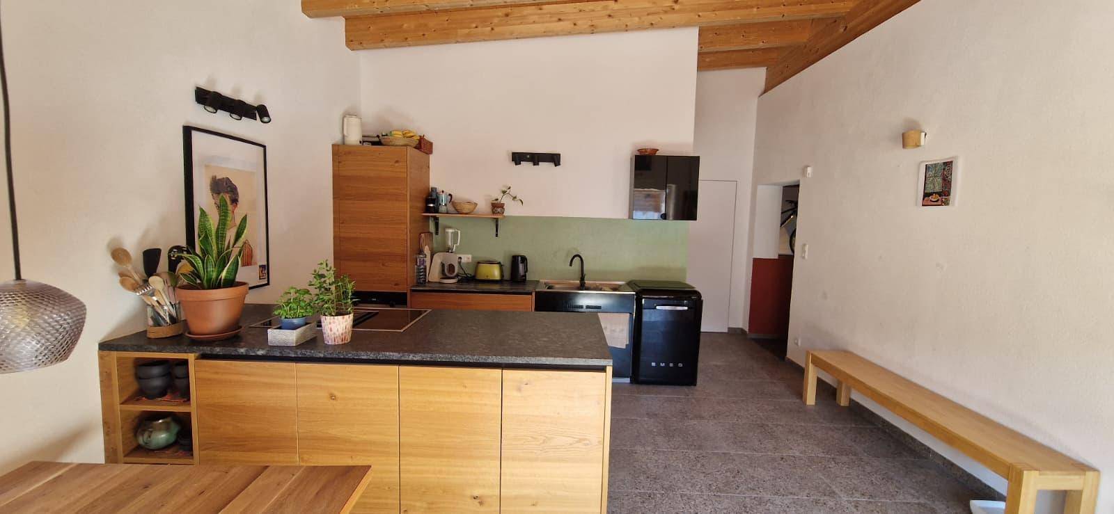 Moderne Holzküche mit dunkler Arbeitsplatte, integrierten Geräten und offenem Stauraum.