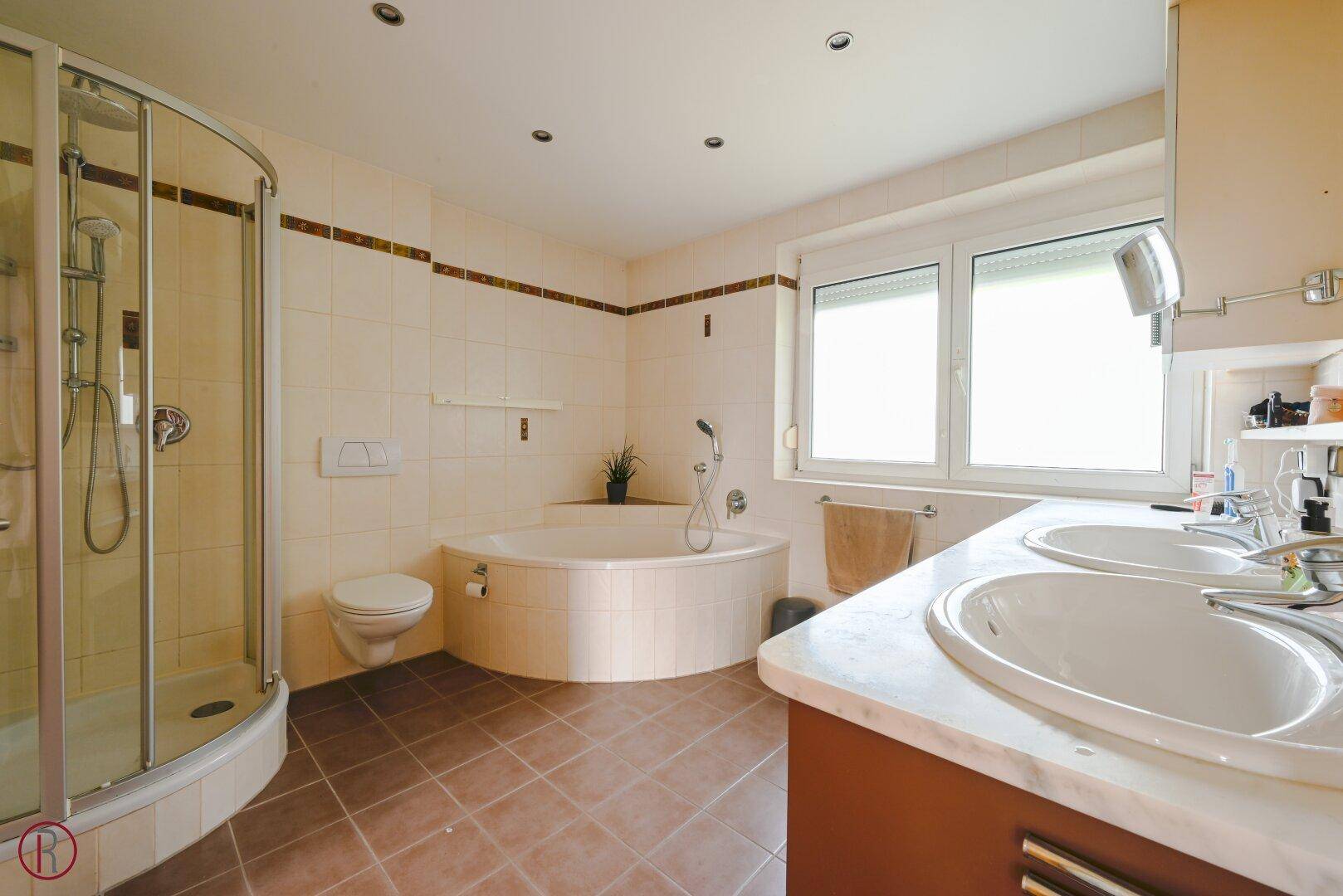 Geräumiges Badezimmer mit Eckbadewanne, separater Dusche, Doppelwaschbecken und Fenster.