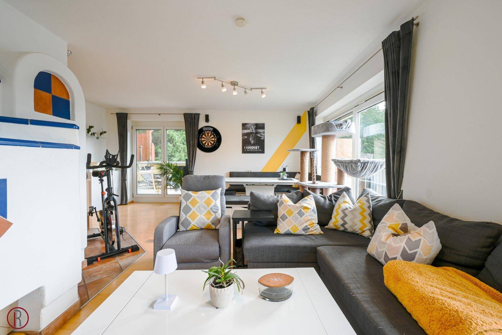 Helles Wohnzimmer mit großem Sofa, Couchtisch und Kachelofen, ideal für gesellige Abende.
