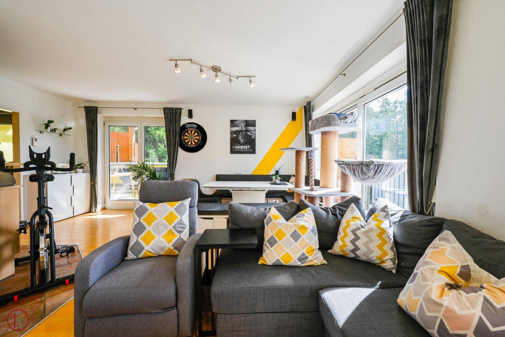 Offener Wohn-Essbereich mit Sofa, Esstisch und Zugang zum Balkon, hell und modern eingerichtet.