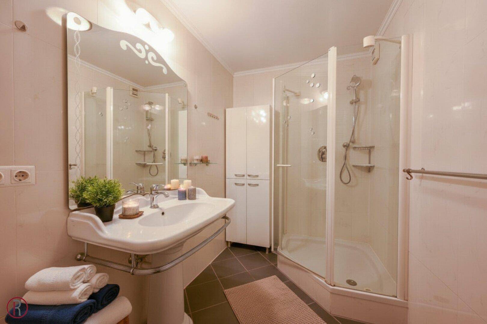 Funktionales Badezimmer mit Dusche, Waschbecken und hellen Fliesen.