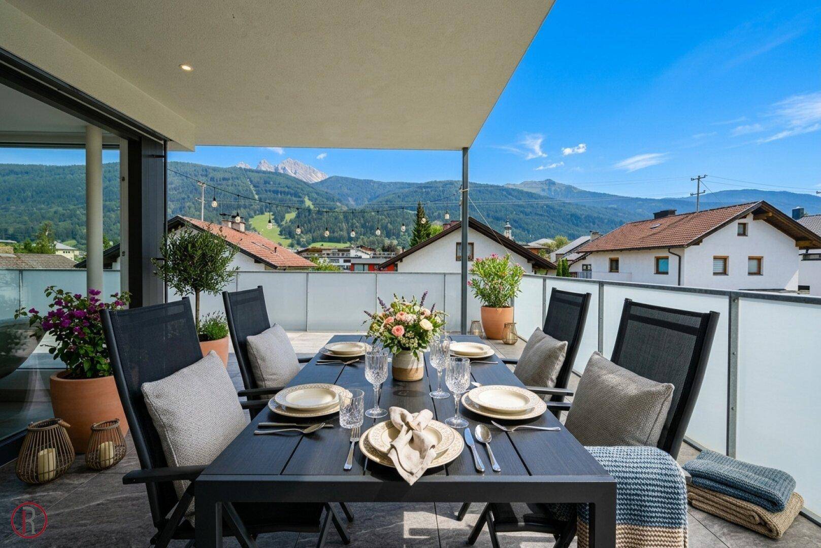 Einladender Essbereich auf der Terrasse mit gedecktem Tisch und malerischem Blick auf die Berge.