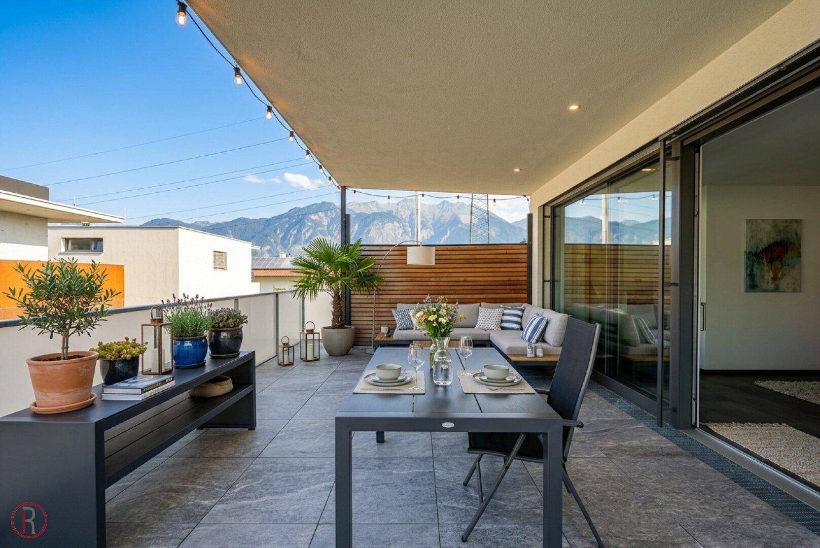 Stilvolle Terrasse mit Ess- und Loungebereich, umgeben von Pflanzen und mit beeindruckendem Bergblick.