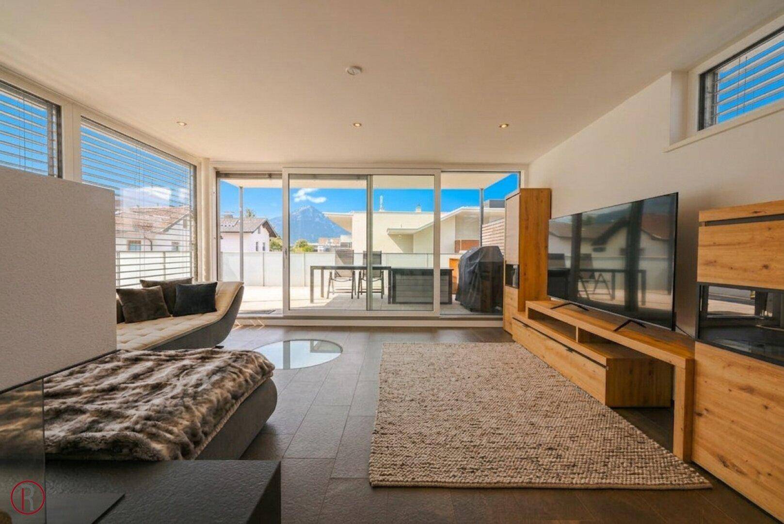 Helles Wohnzimmer mit Zugang zur Terrasse, ausgestattet mit einem bequemen Sofa und einem modernen TV-Möbel.
