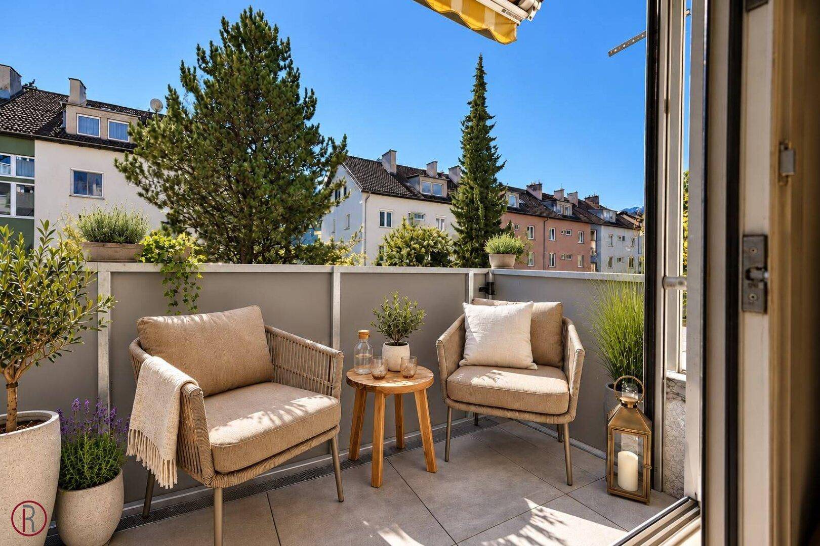 Sonniger Balkon mit bequemen Sitzmöbeln und Blick auf die umliegenden Gebäude.