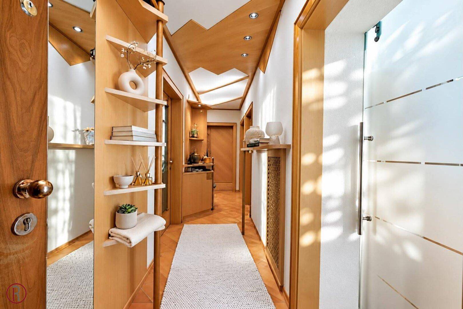 Heller Flur mit Holzvertäfelung, Einbauregalen und indirekter Beleuchtung.