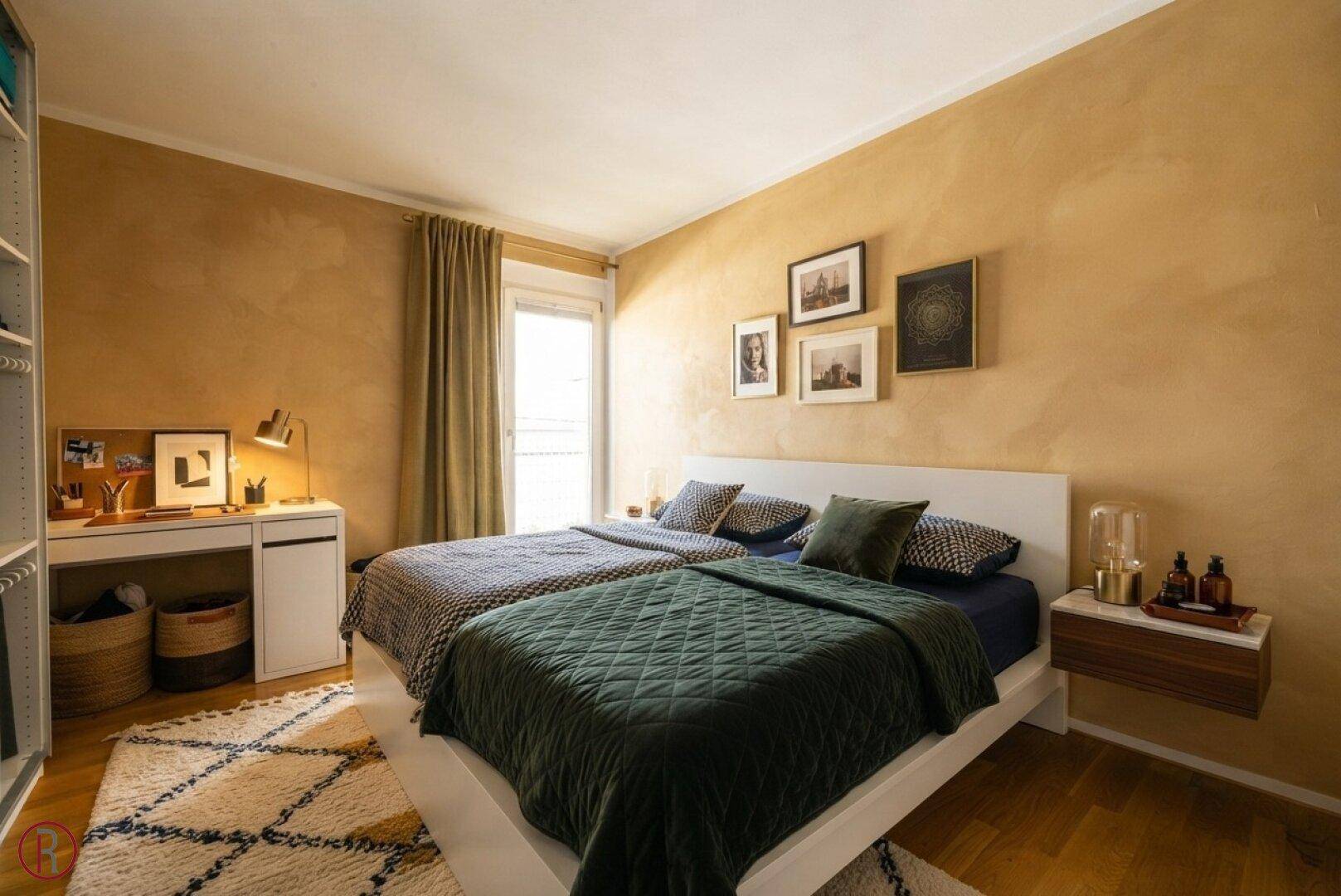 Gemütliches Schlafzimmer mit Doppelbett, warmen Wandfarben und einem kleinen Schreibtisch.