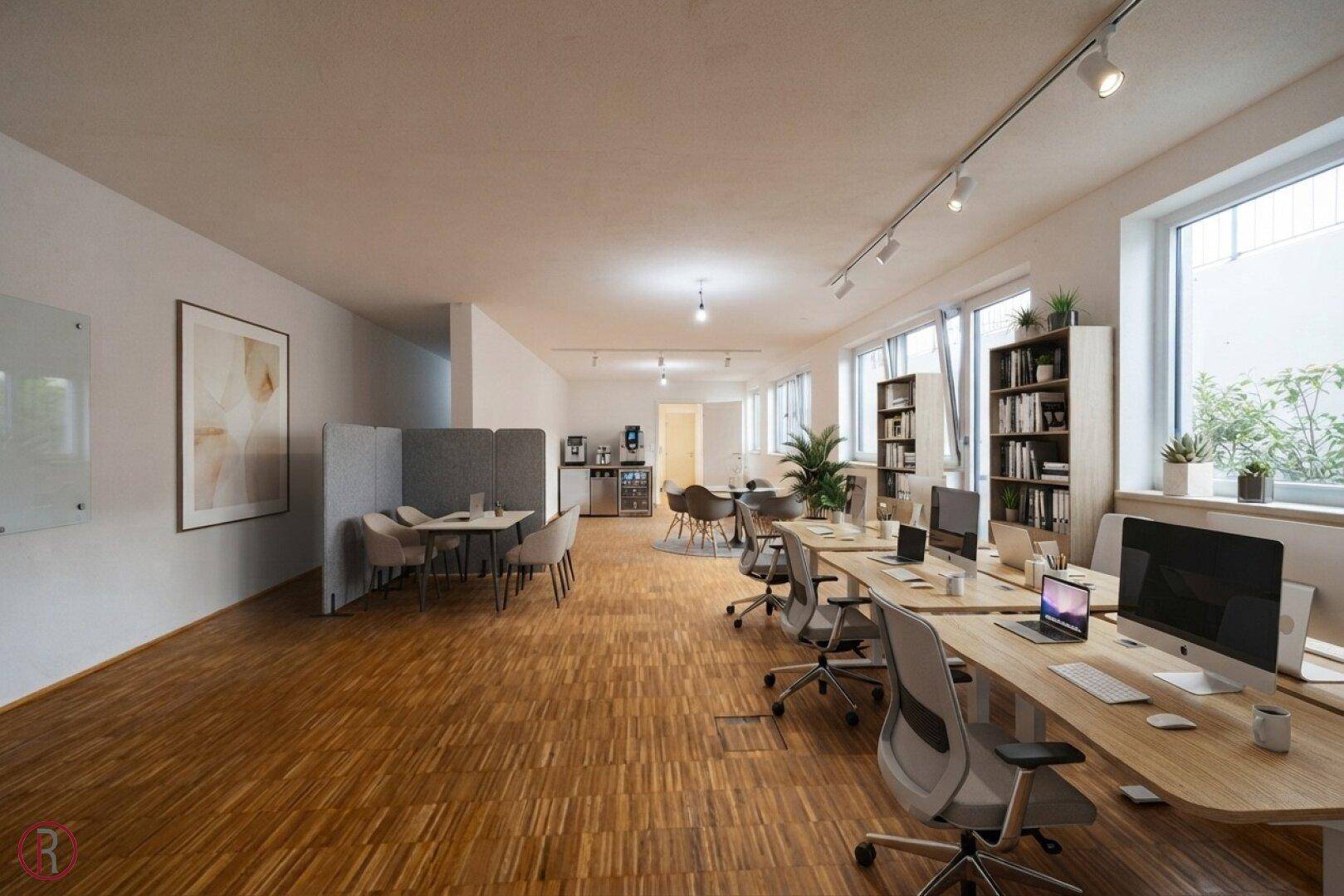 Großraumbüro mit mehreren Arbeitsplätzen, Holzboden und einem Bereich für informelle Besprechungen.