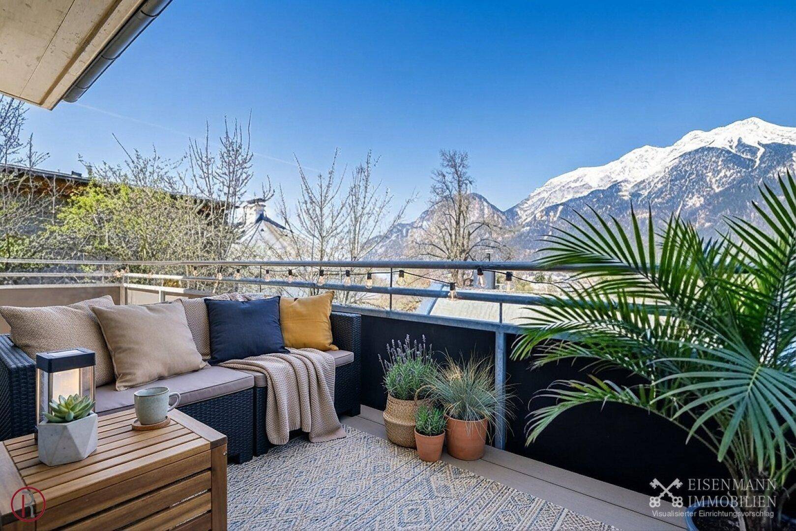 Sonniger Balkon mit bequemen Loungemöbeln und atemberaubendem Panoramablick auf die Berge.