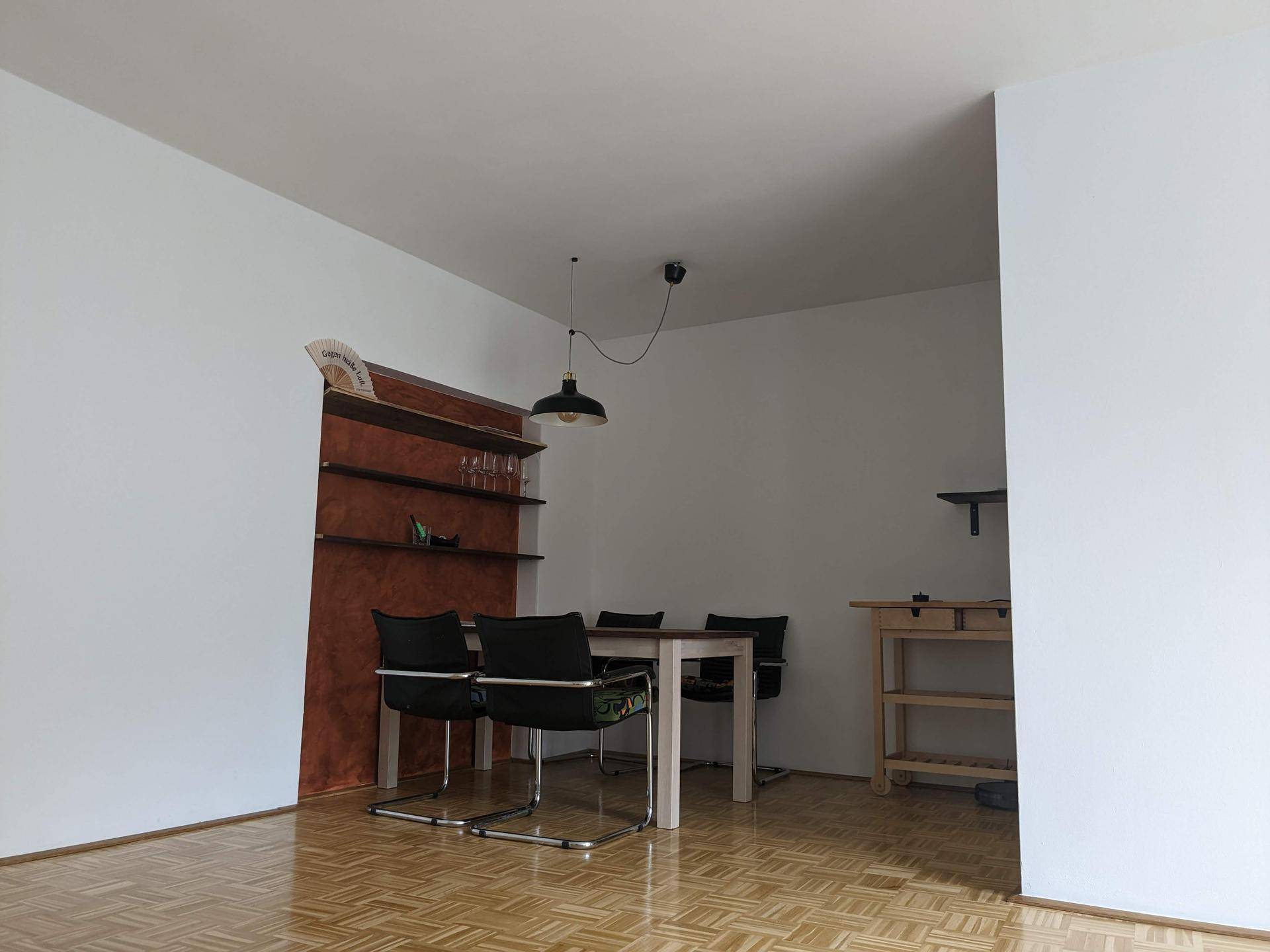 Essbereich mit Holztisch, schwarzen Stühlen und einer dekorativen Wandnische mit Regalen.