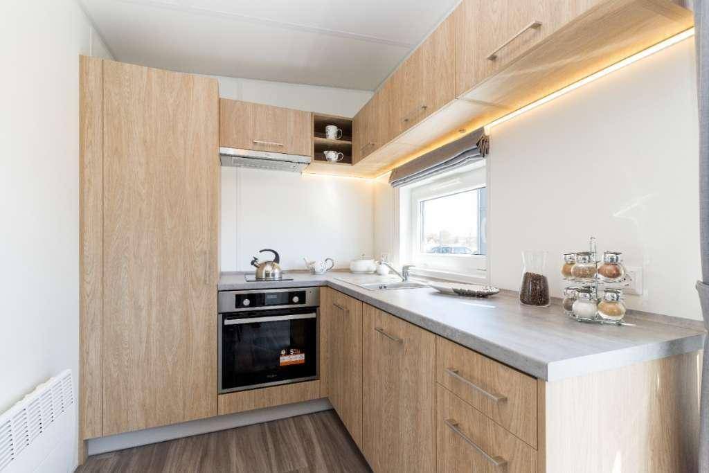 Funktionale Küche mit hellen Holzschränken, integrierten Geräten und Fenster für Tageslicht.
