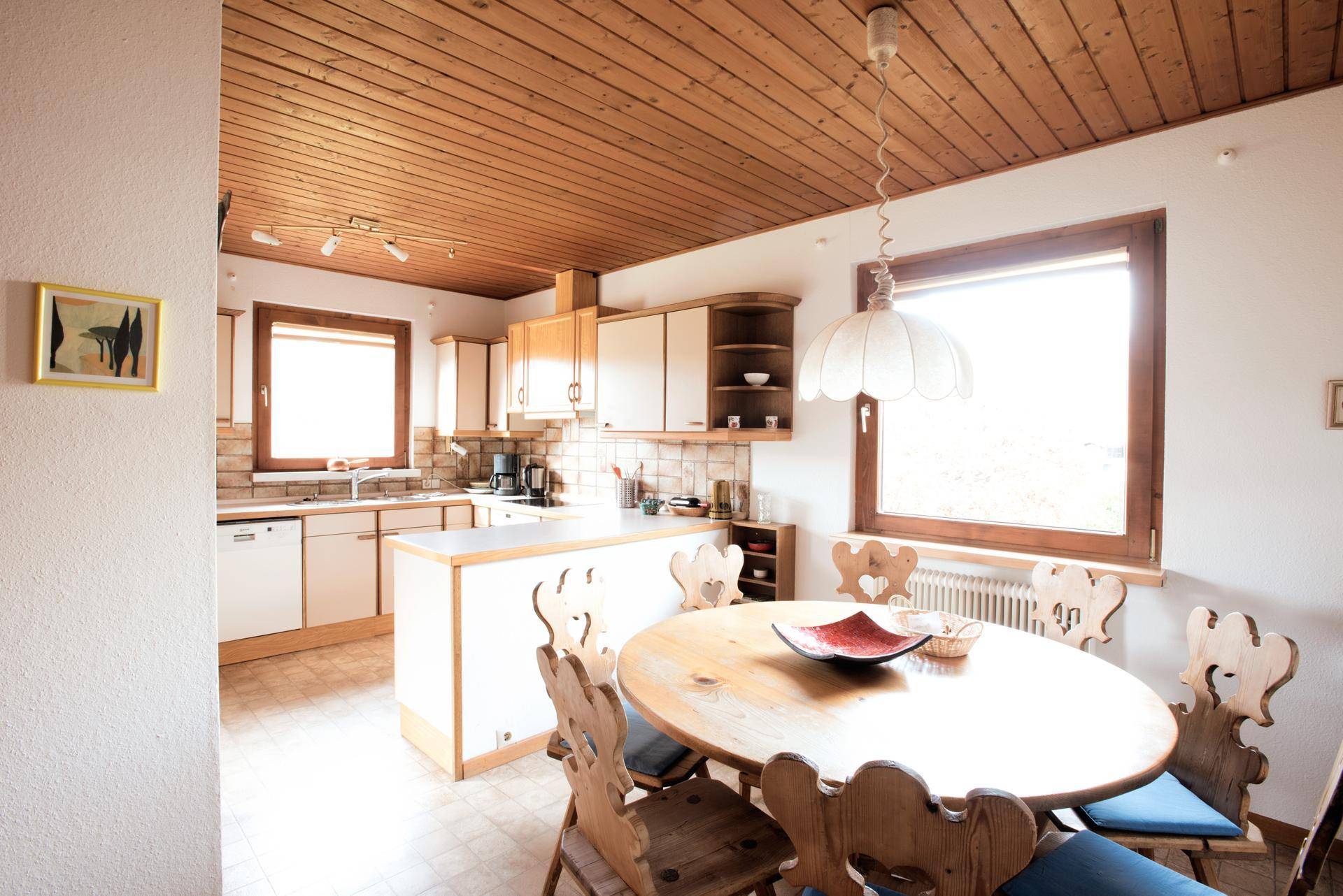 Helle Küche mit Essbereich, Holzdecke und traditionellen Holzstühlen, ideal für Familienmahlzeiten.