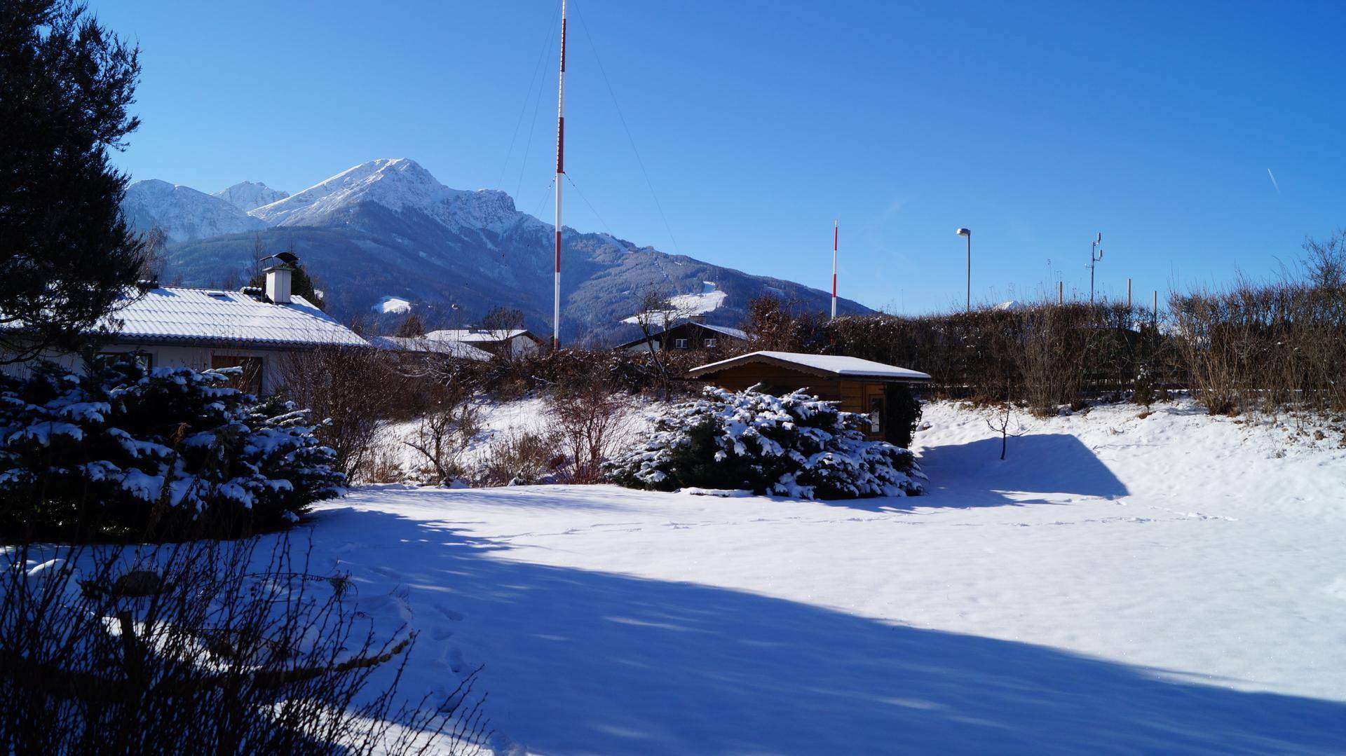 Winterlicher Garten mit schneebedeckter Landschaft und klarem Blick auf die majestätischen Berge.