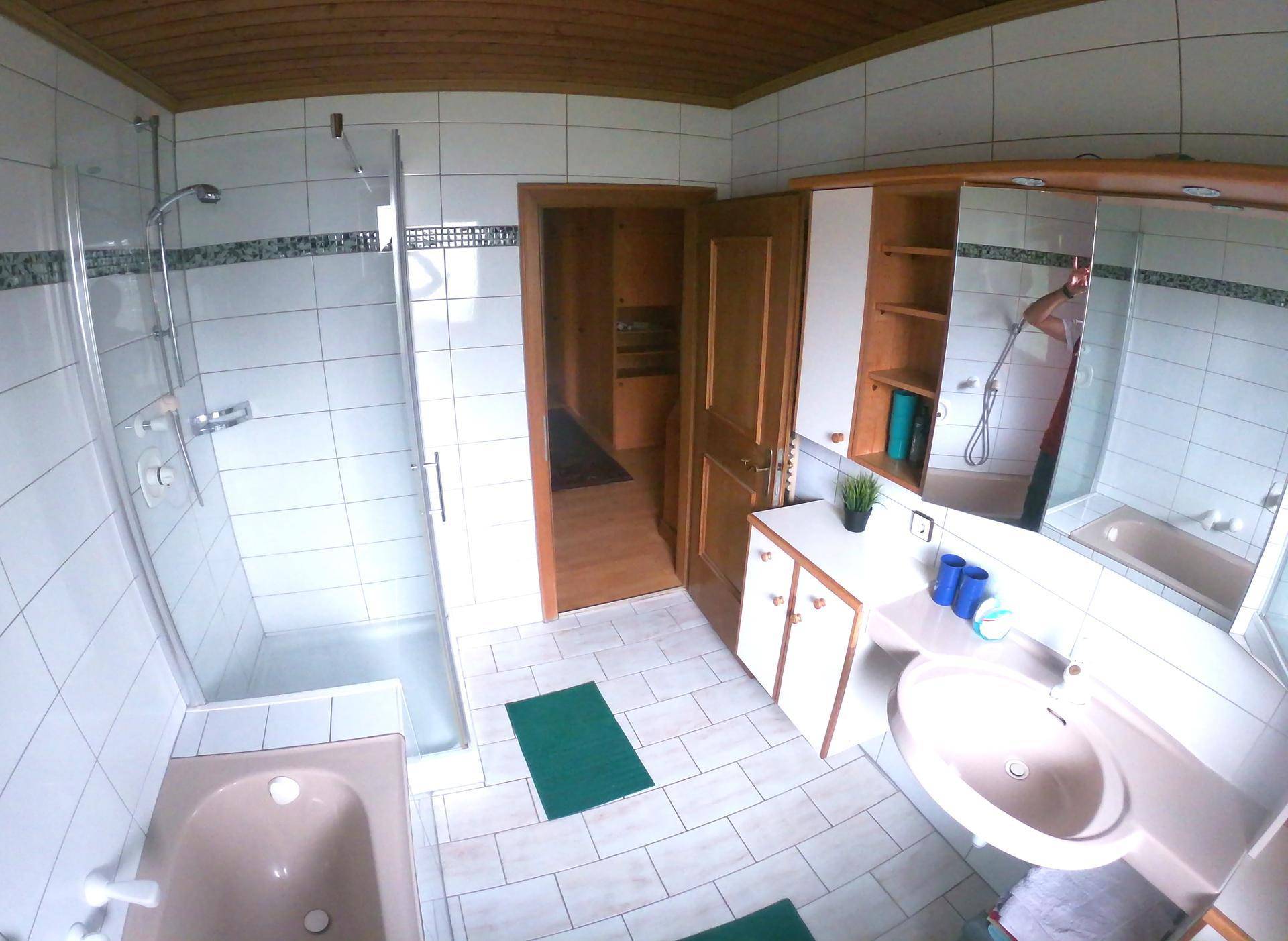 Funktionales Badezimmer mit Duschkabine, Badewanne und Waschtisch, ausgestattet mit Spiegelschrank.