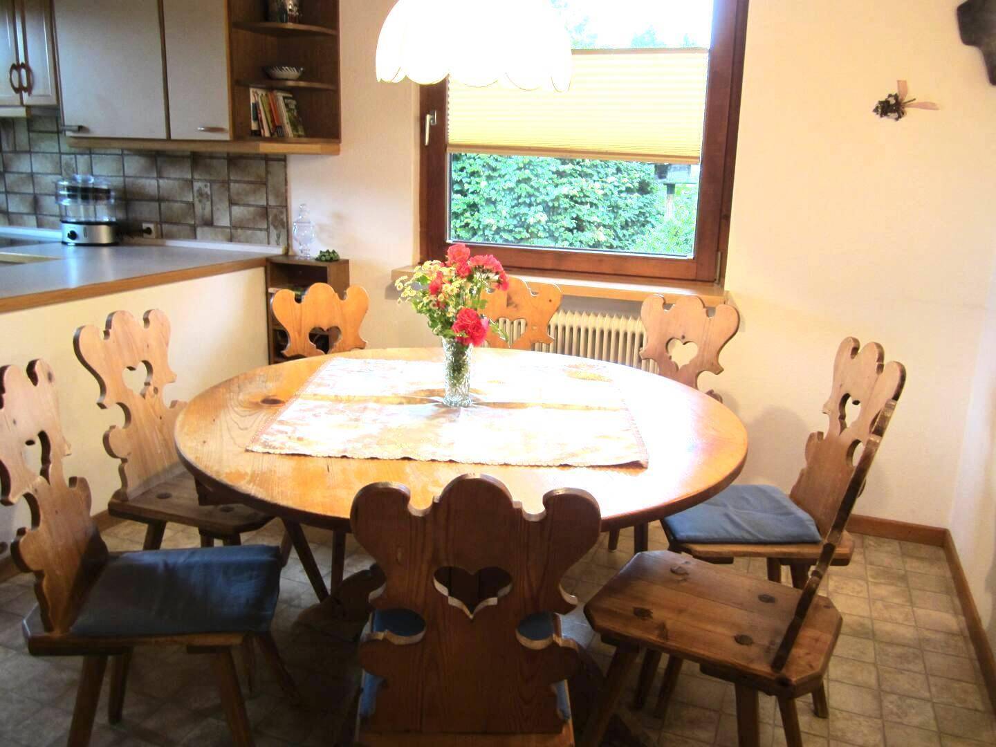 Gemütlicher Essbereich in der Küche mit traditionellen Holzstühlen und Blick auf den grünen Garten.