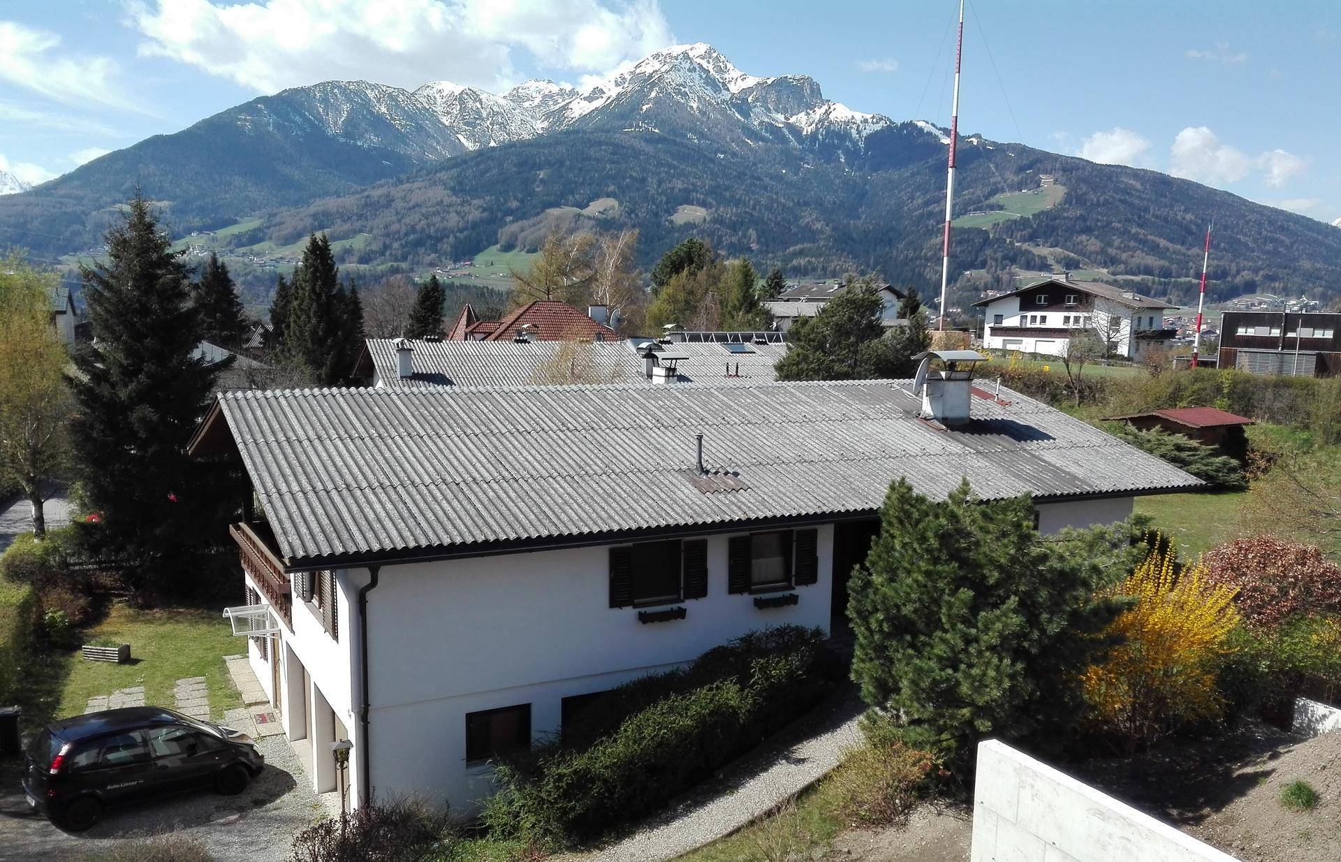 Luftaufnahme eines Hauses mit grauen Dachziegeln und weitem Blick auf die umliegende Berglandschaft.