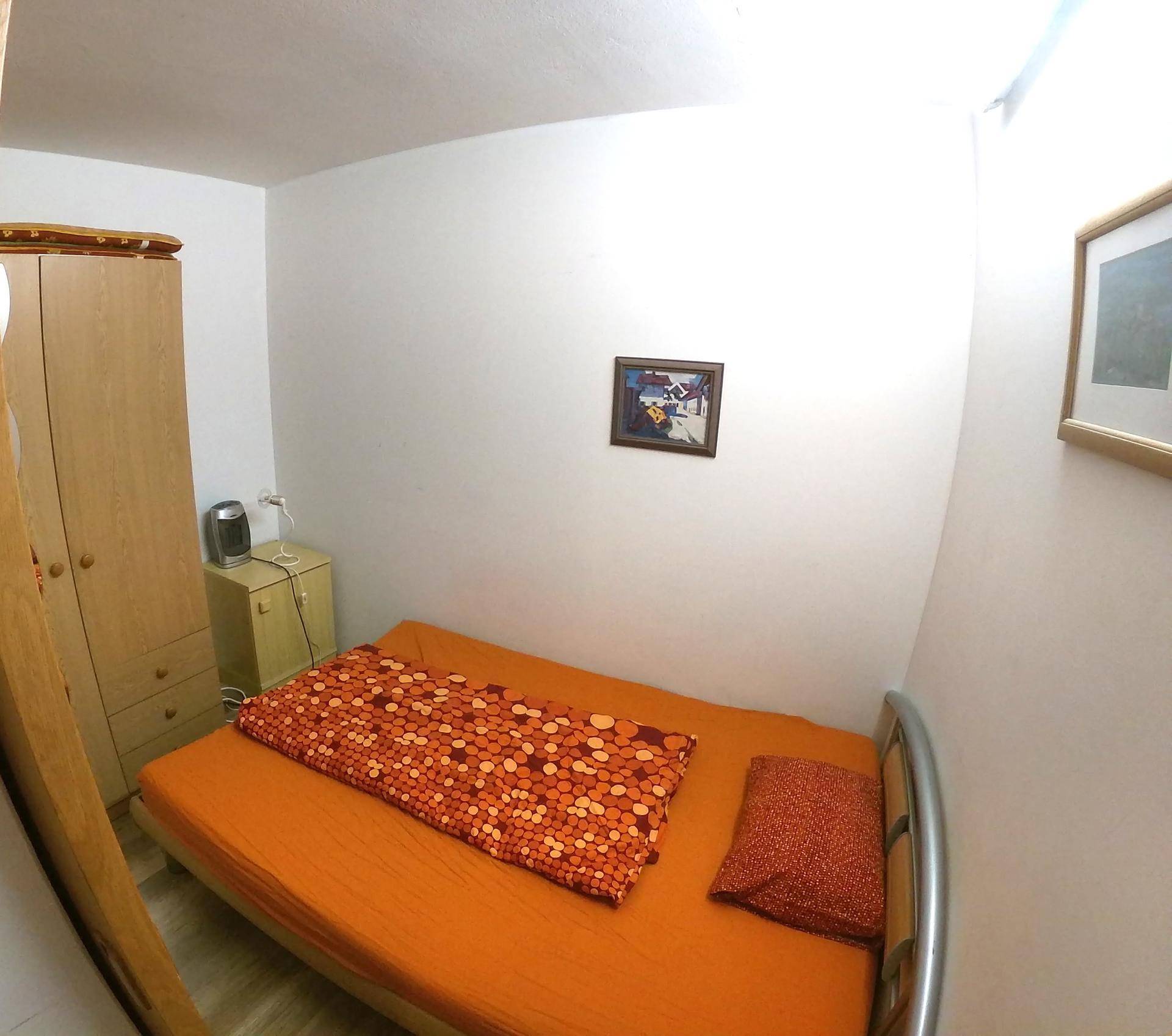 Kleines Schlafzimmer mit Einzelbett, Kleiderschrank und einfacher Einrichtung.