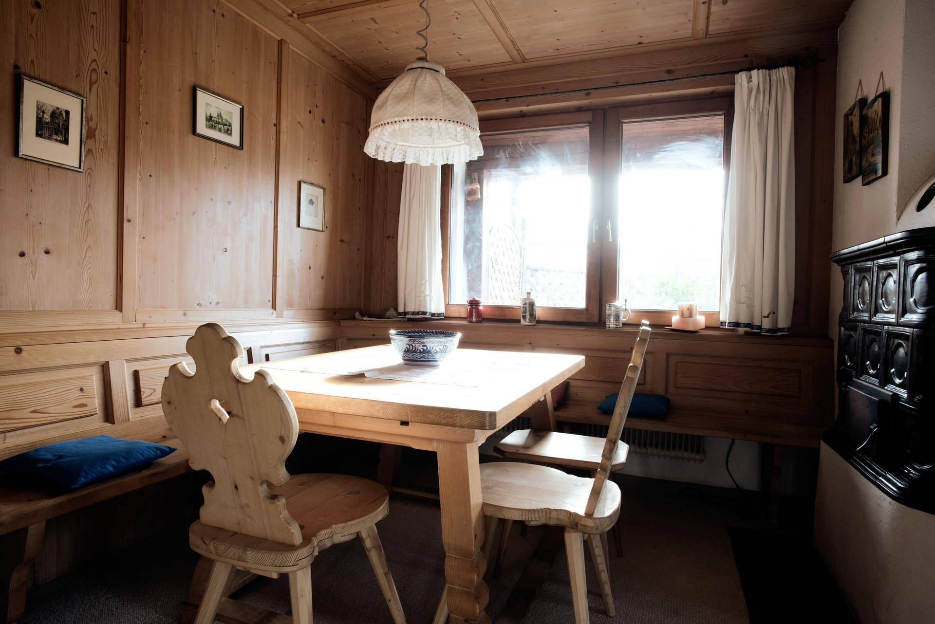 Rustikaler Essbereich mit Holztäfelung, traditionellen Möbeln und einem Kachelofen für gemütliche Abende.