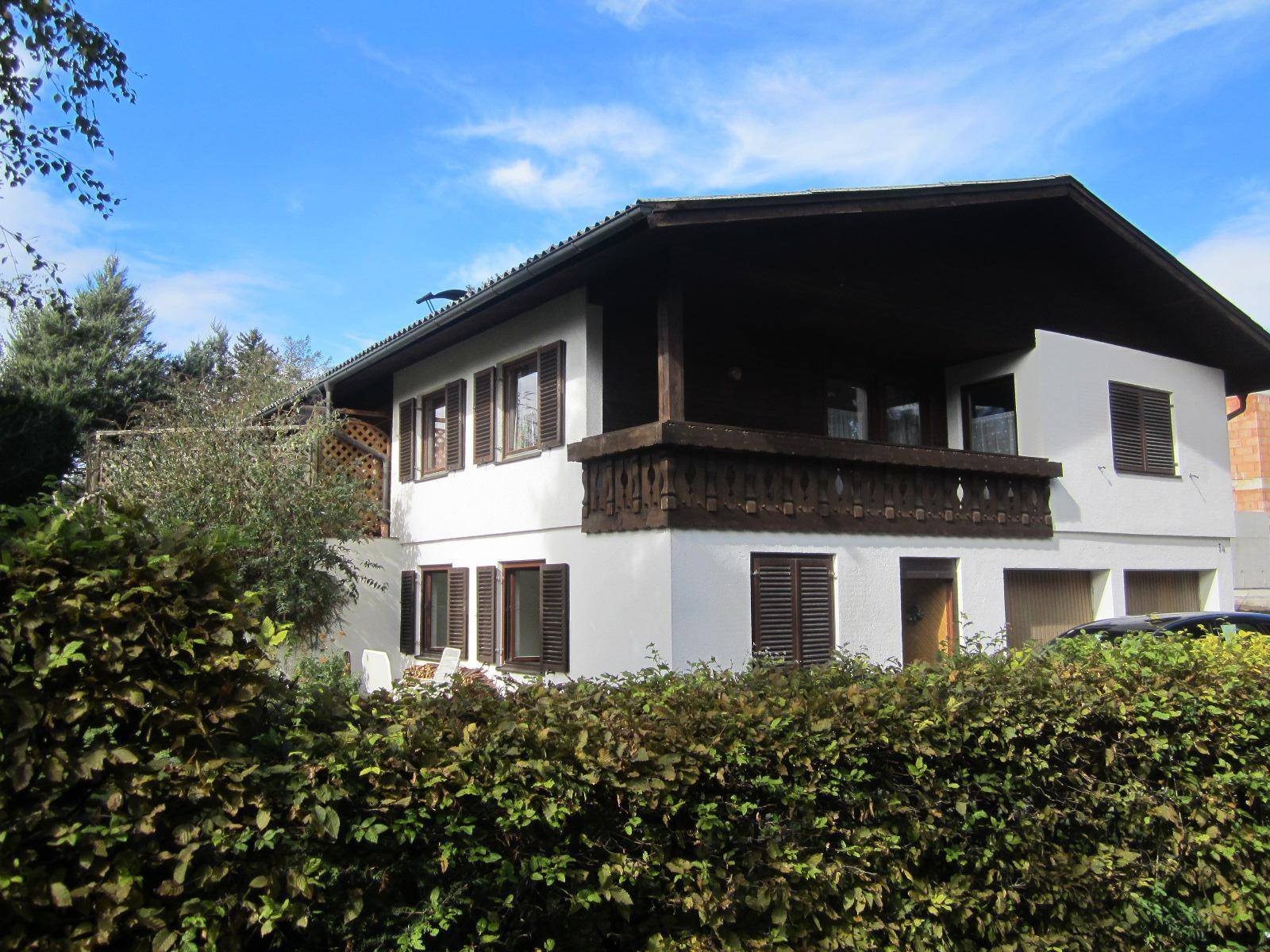 Traditionelles Haus mit weißer Fassade, Holzdetails und einem Balkon mit geschnitztem Geländer.