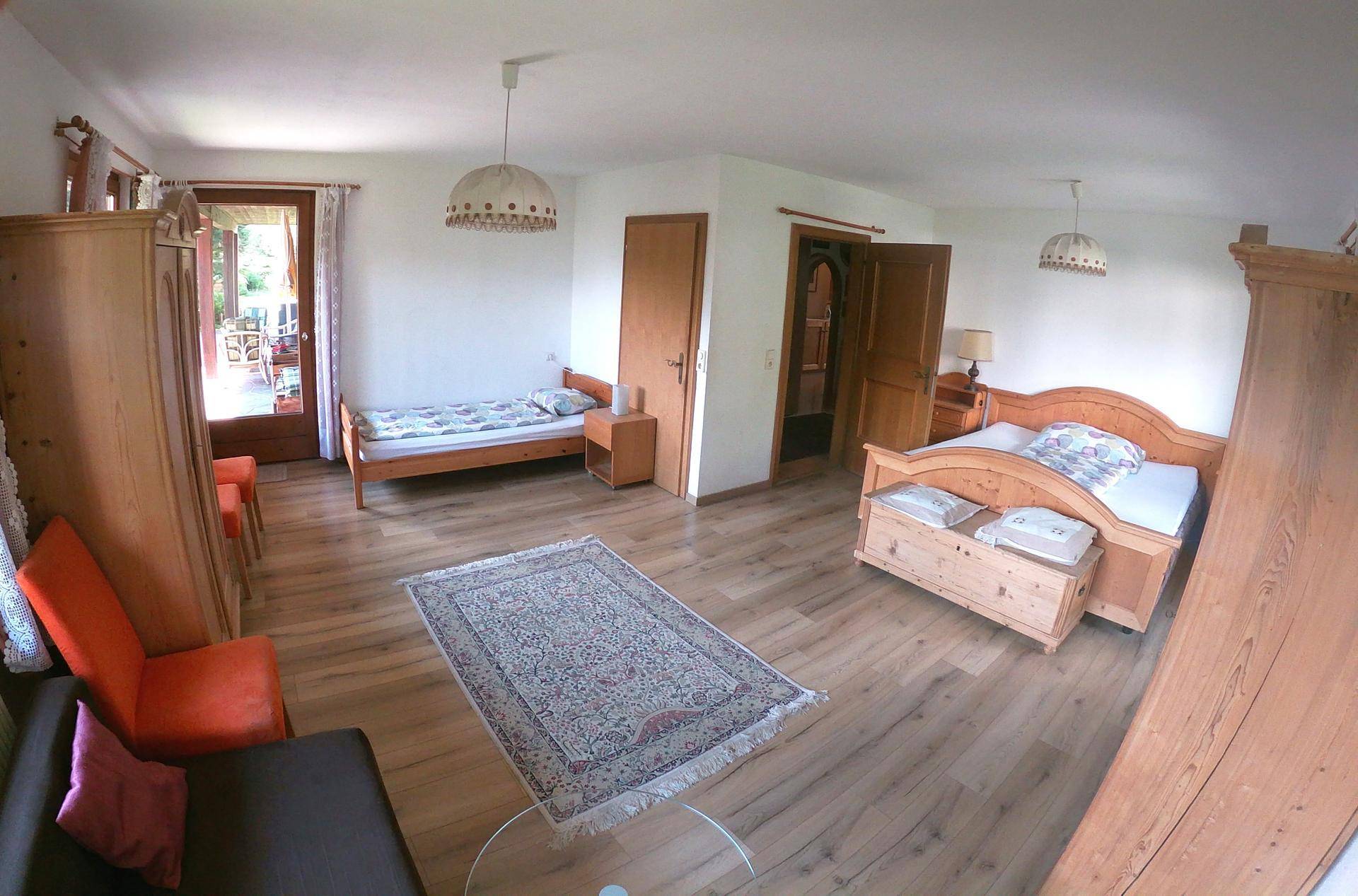 Helles Schlafzimmer mit zwei Einzelbetten, Holzmöbeln und direktem Zugang zu einem Außenbereich.