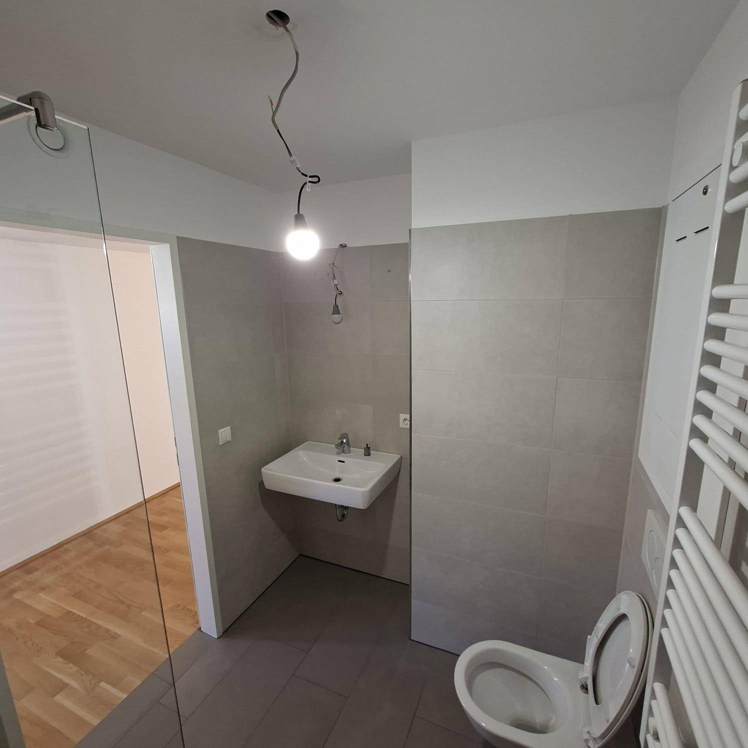 Modernes Badezimmer mit Fliesen, Waschbecken und Toilette, noch in Fertigstellung.