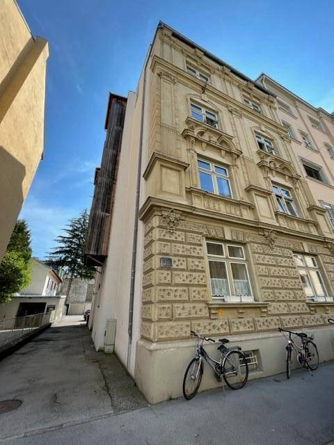 Historisches Gebäude mit reich verzierter Fassade und Fahrrädern davor an einem sonnigen Tag.