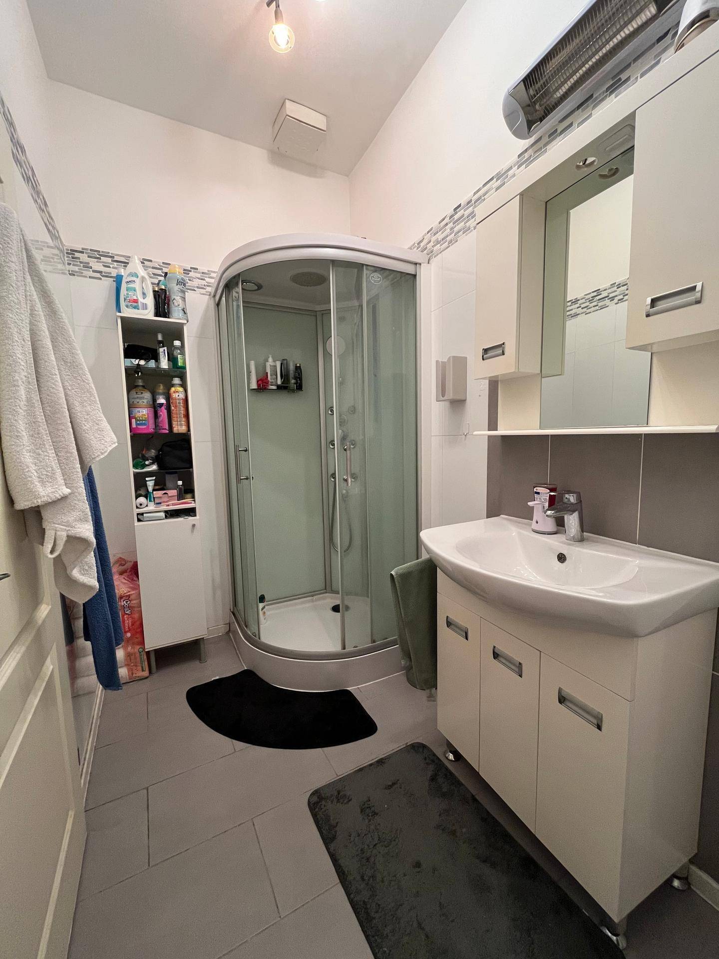 Modernes Badezimmer mit Duschkabine, Waschbecken und Spiegelschrank.