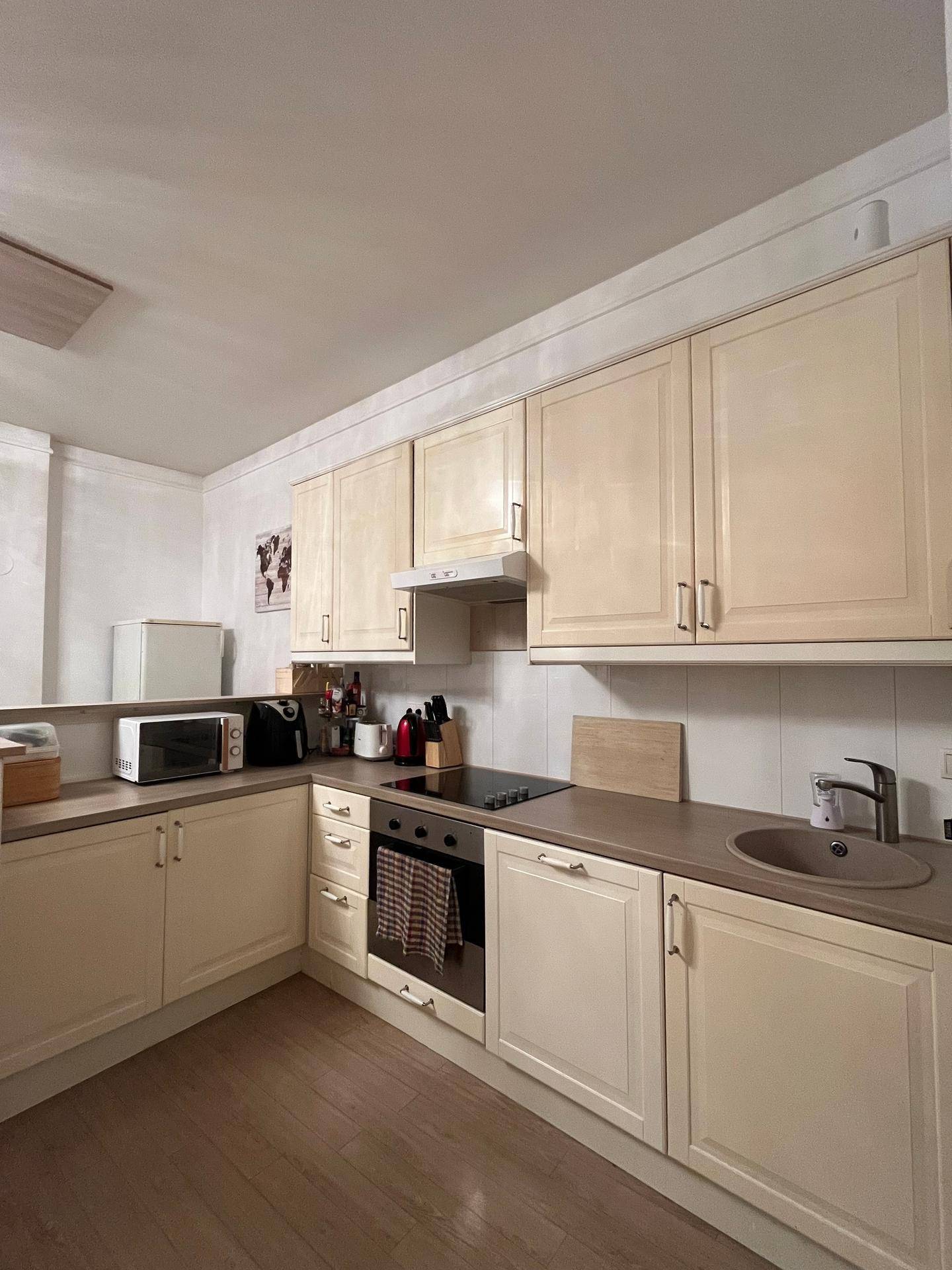 Funktionale Küche mit hellen Holzschränken, Induktionskochfeld und Mikrowelle.