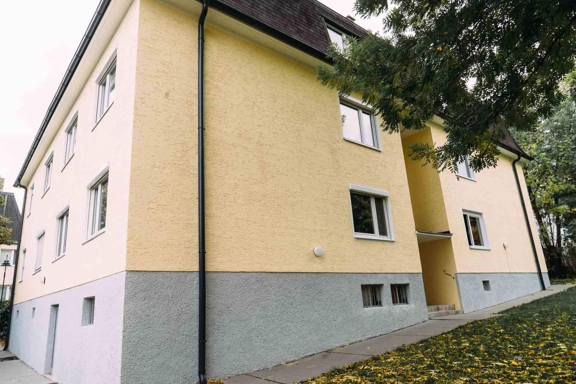 Außenansicht des Gebäudes mit gelber und grauer Fassade.