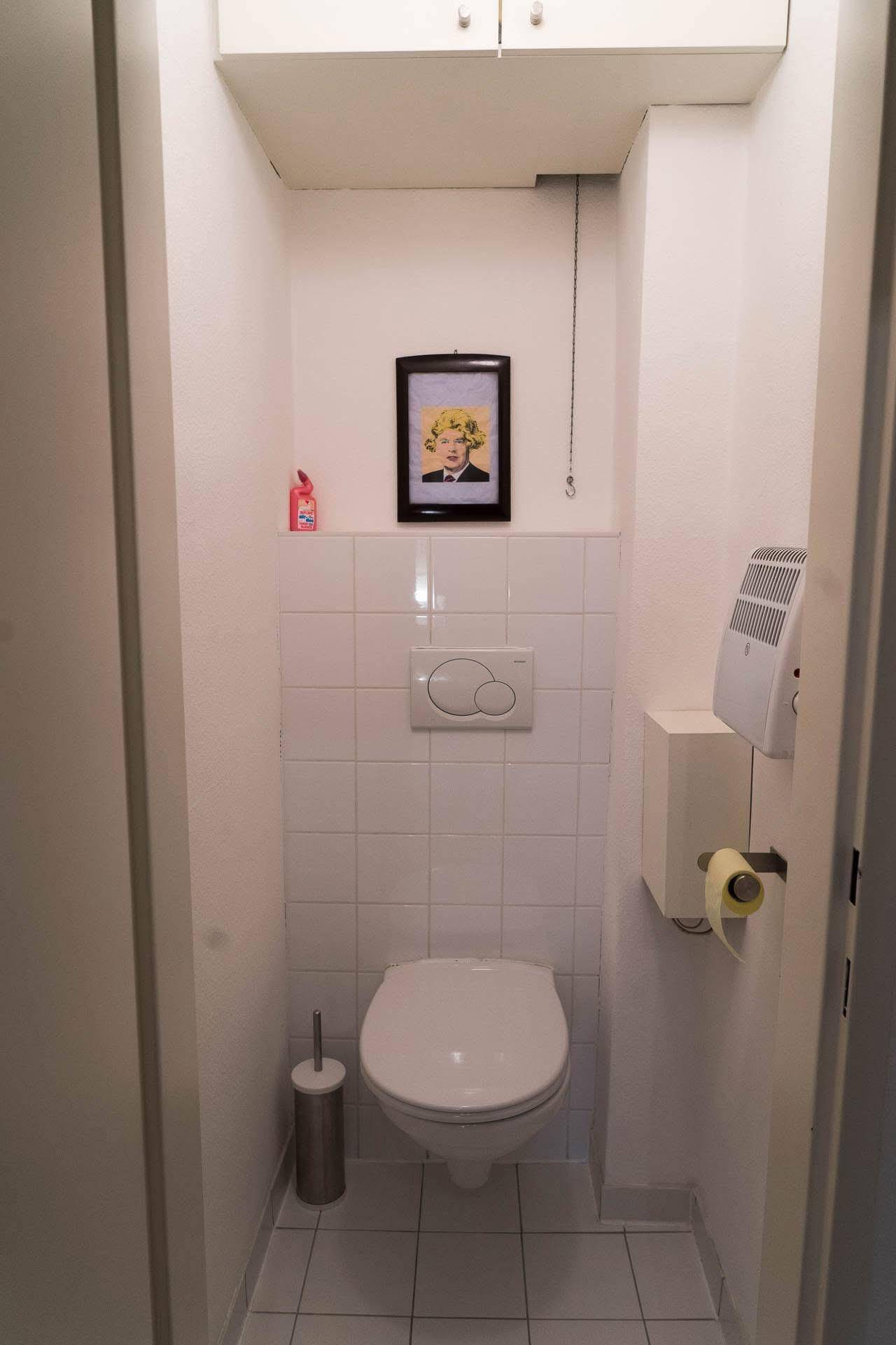 Separates WC mit wandhängender Toilette und weißen Fliesen.