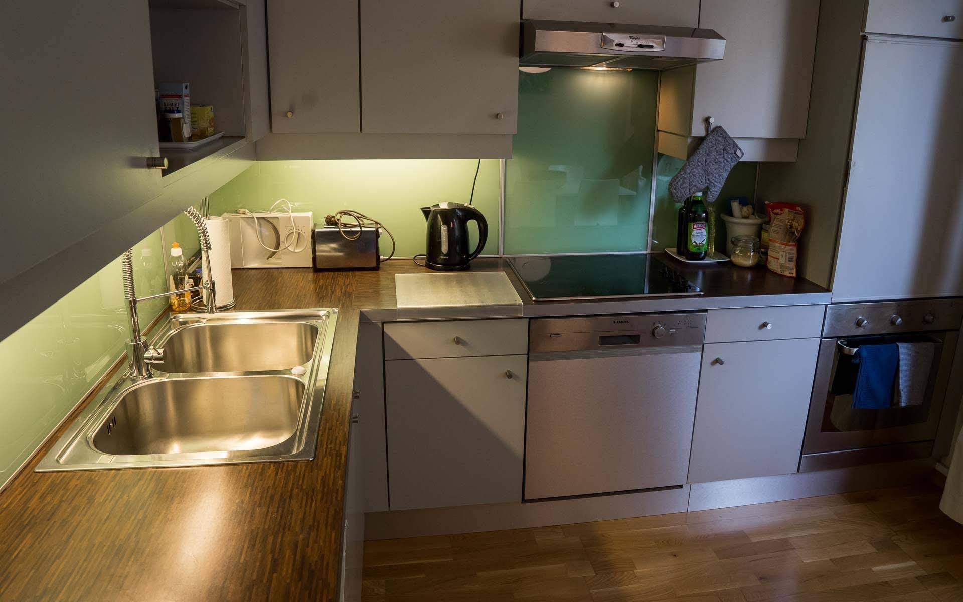 Küchenzeile mit Spüle, Geschirrspüler, Induktionskochfeld und integriertem Backofen.