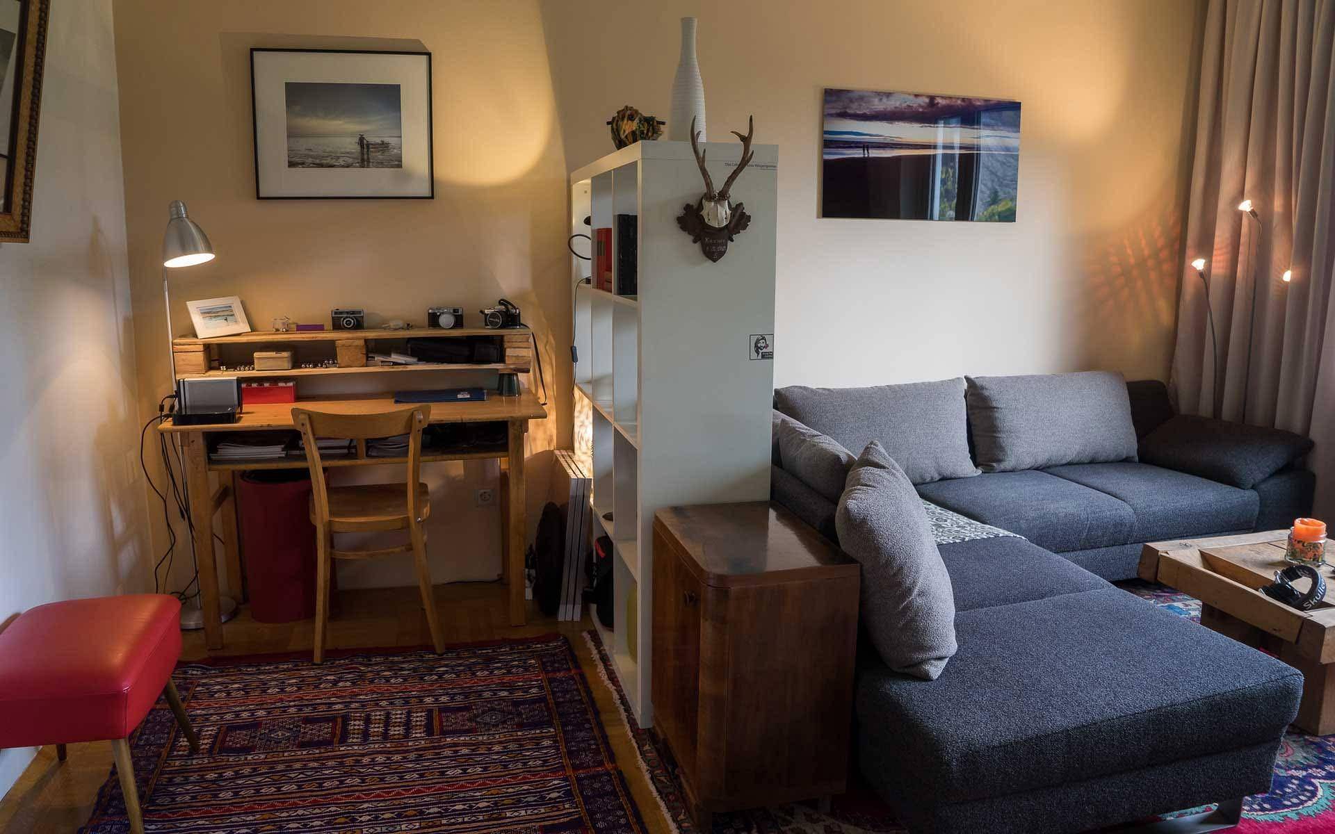 Wohnzimmer mit Arbeitsbereich, Bücherregal und gemütlichem Sofa.