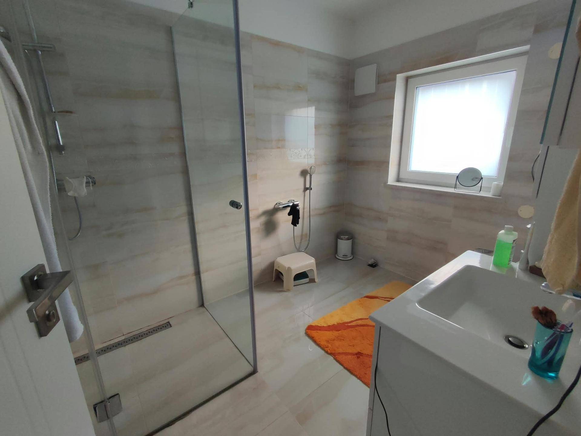 Modernes Badezimmer mit ebenerdiger Dusche, Einzelwaschbecken und Fenster.