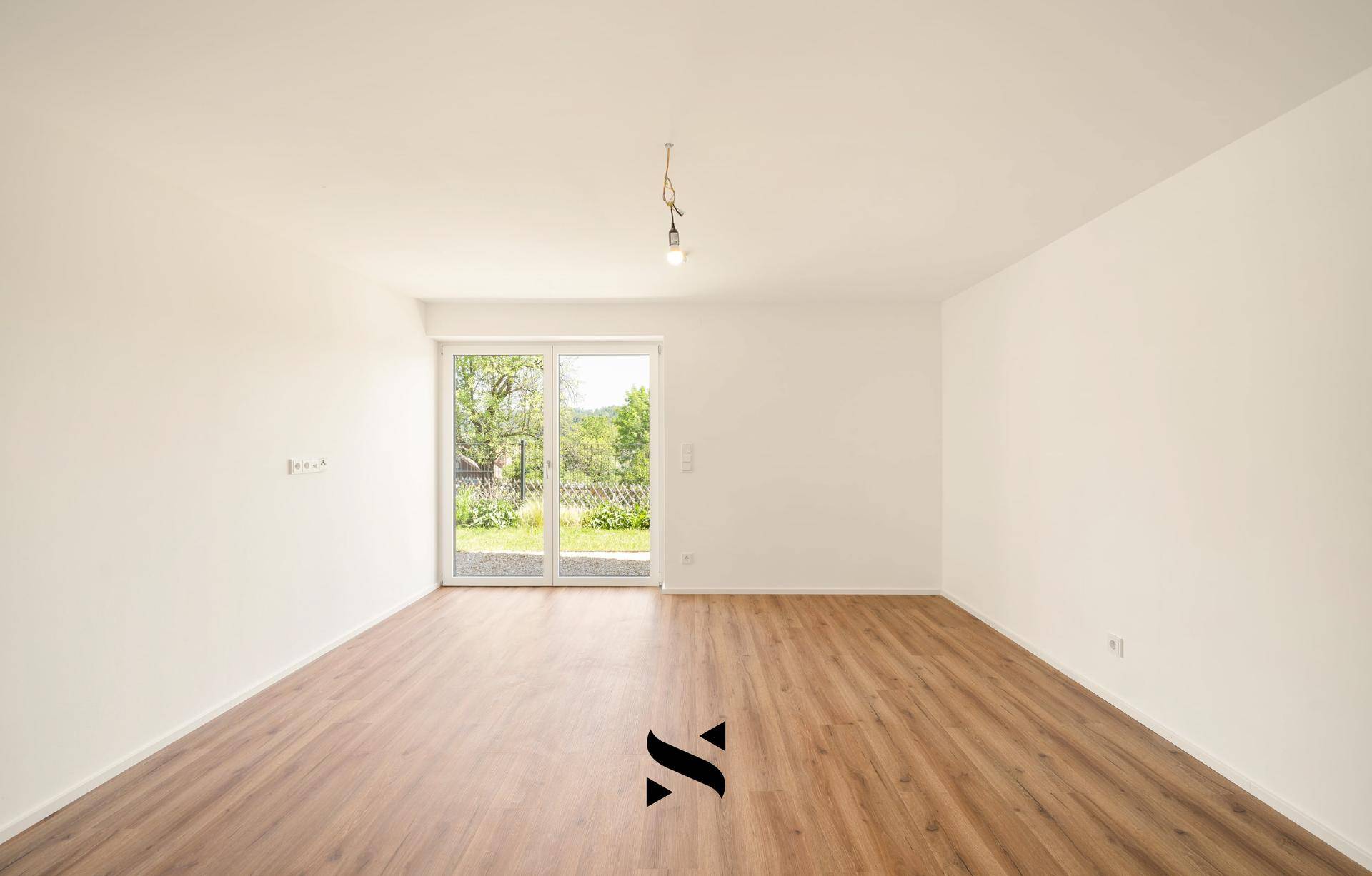 Geräumiges, helles Zimmer mit Laminatboden und Schiebetür zum Gartenbereich.