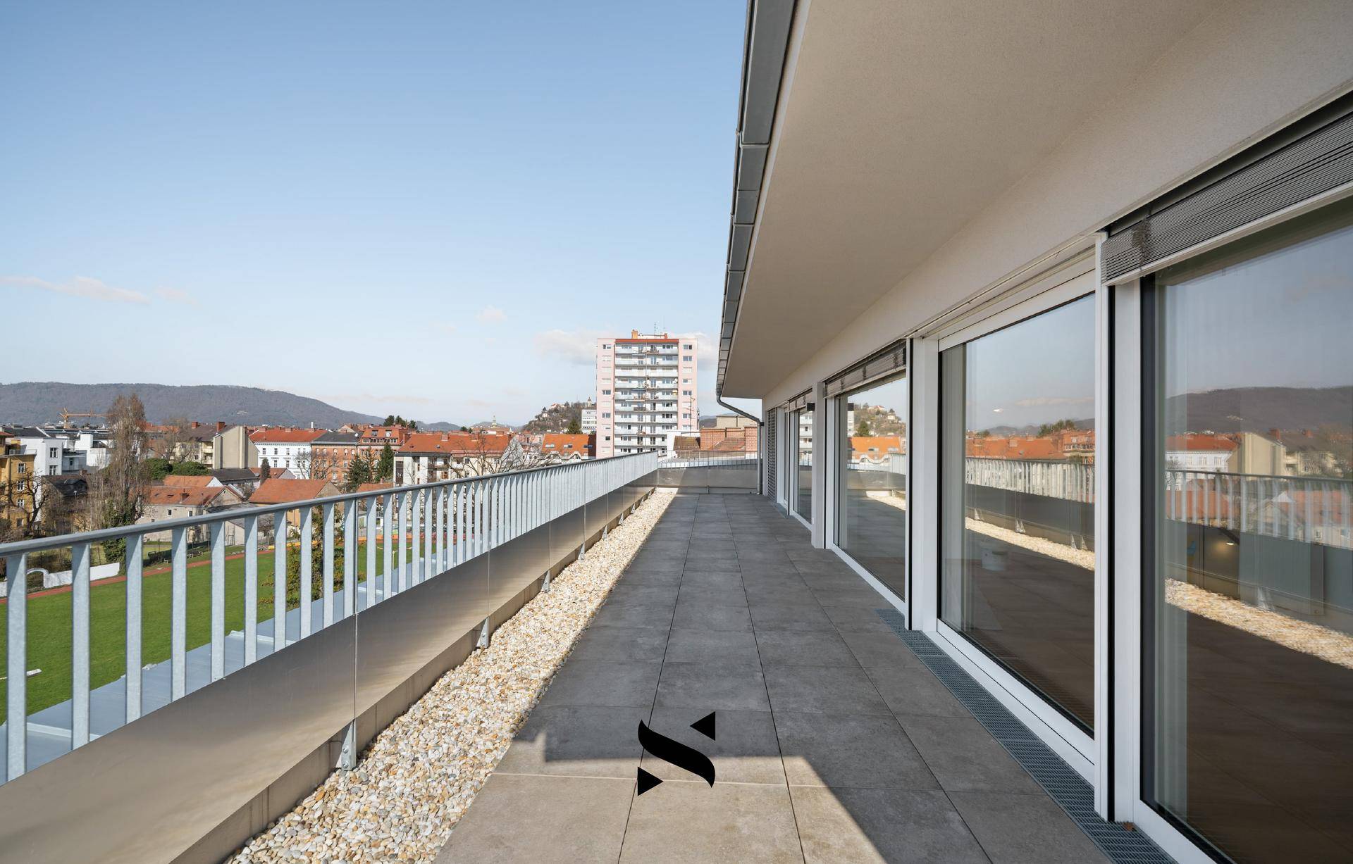Geräumige Dachterrasse mit Fliesenboden und weitem Blick über die Stadt und die Landschaft.