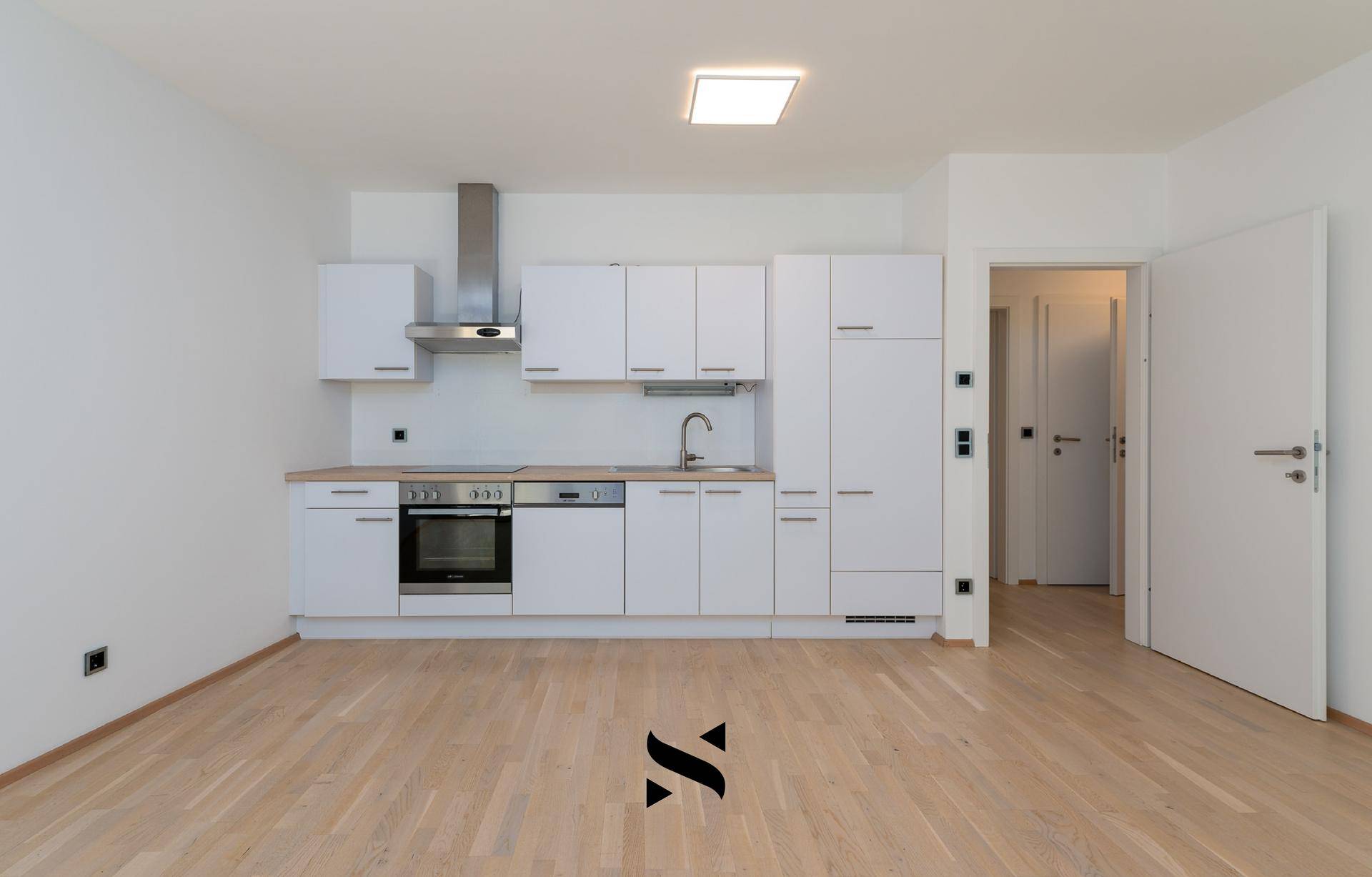 Moderne, eingebaute Küchenzeile mit weißen Schränken und Holz-Arbeitsplatte in einem offenen Raum.