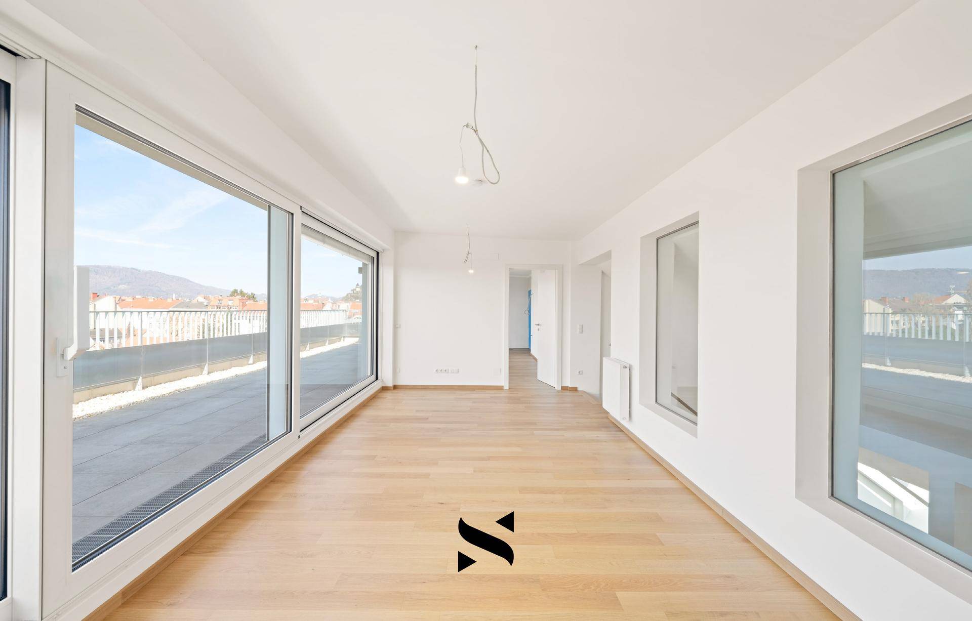 Lichtdurchfluteter Wohnbereich mit Parkettboden und breiter Fensterfront zur Terrasse.