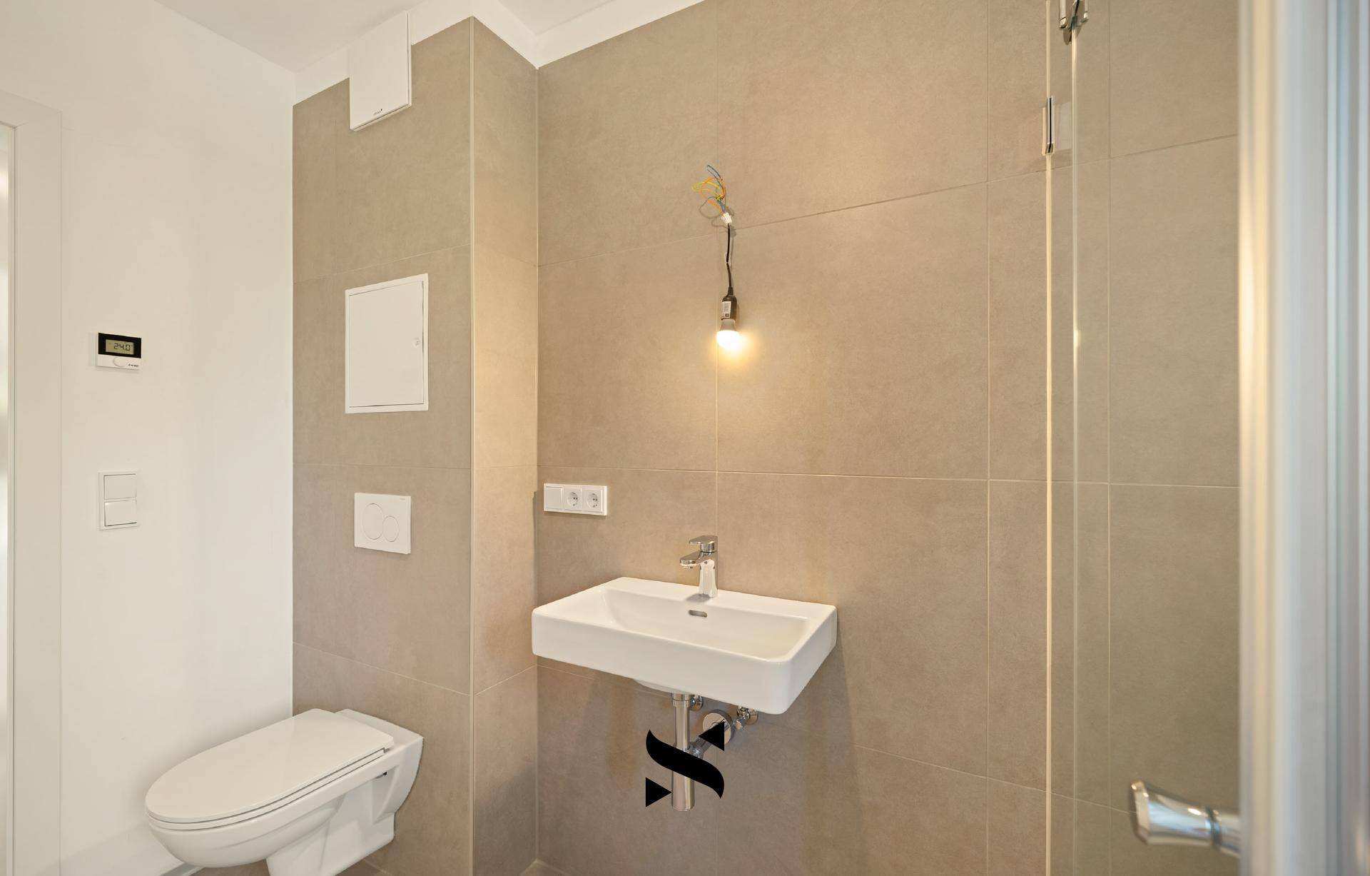 Detailansicht eines modernen Badezimmers mit Wand-WC, Waschbecken und Duschbereich.