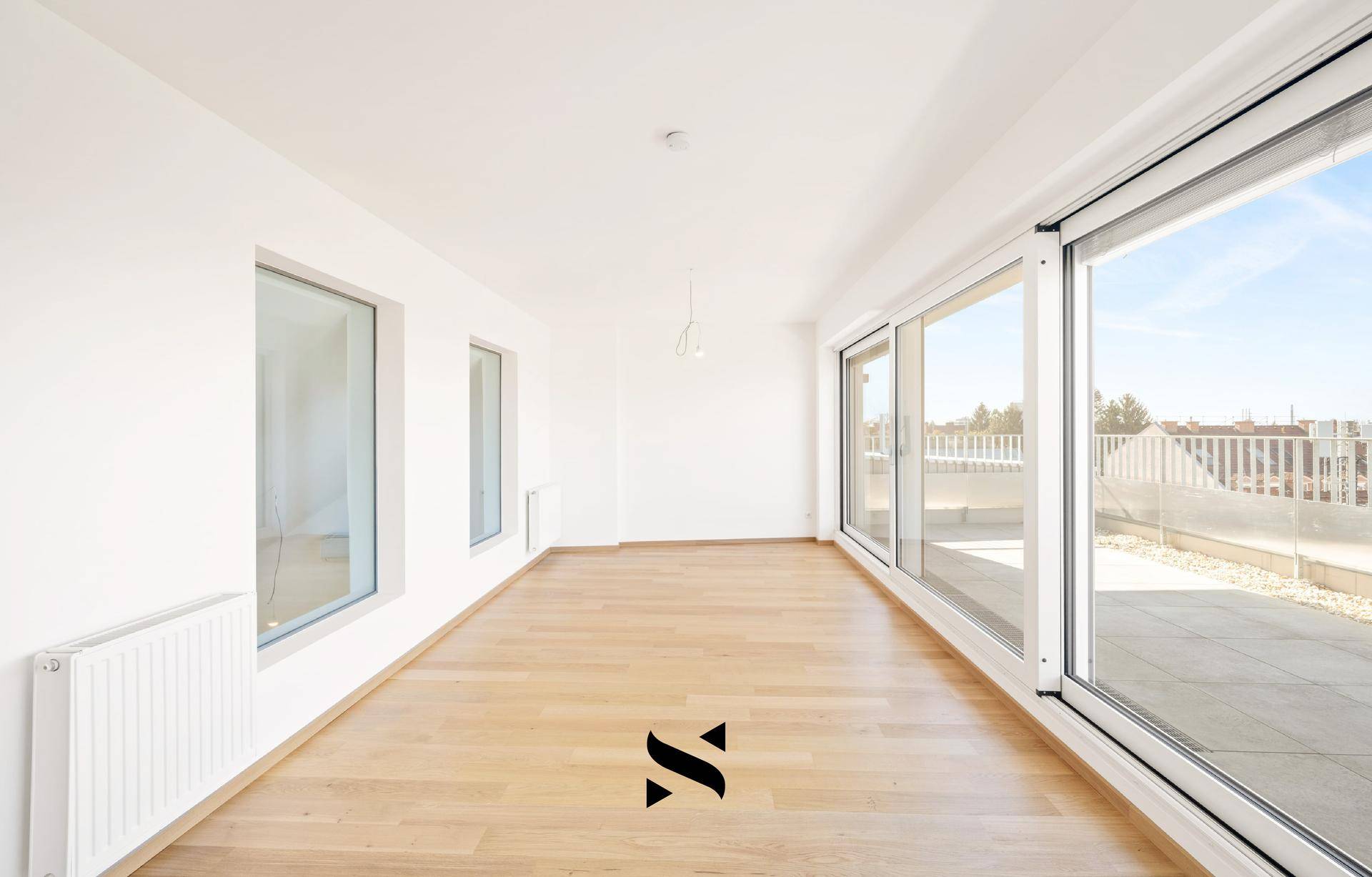 Heller Wohnraum mit Parkettboden und großen Schiebetüren zur Dachterrasse.