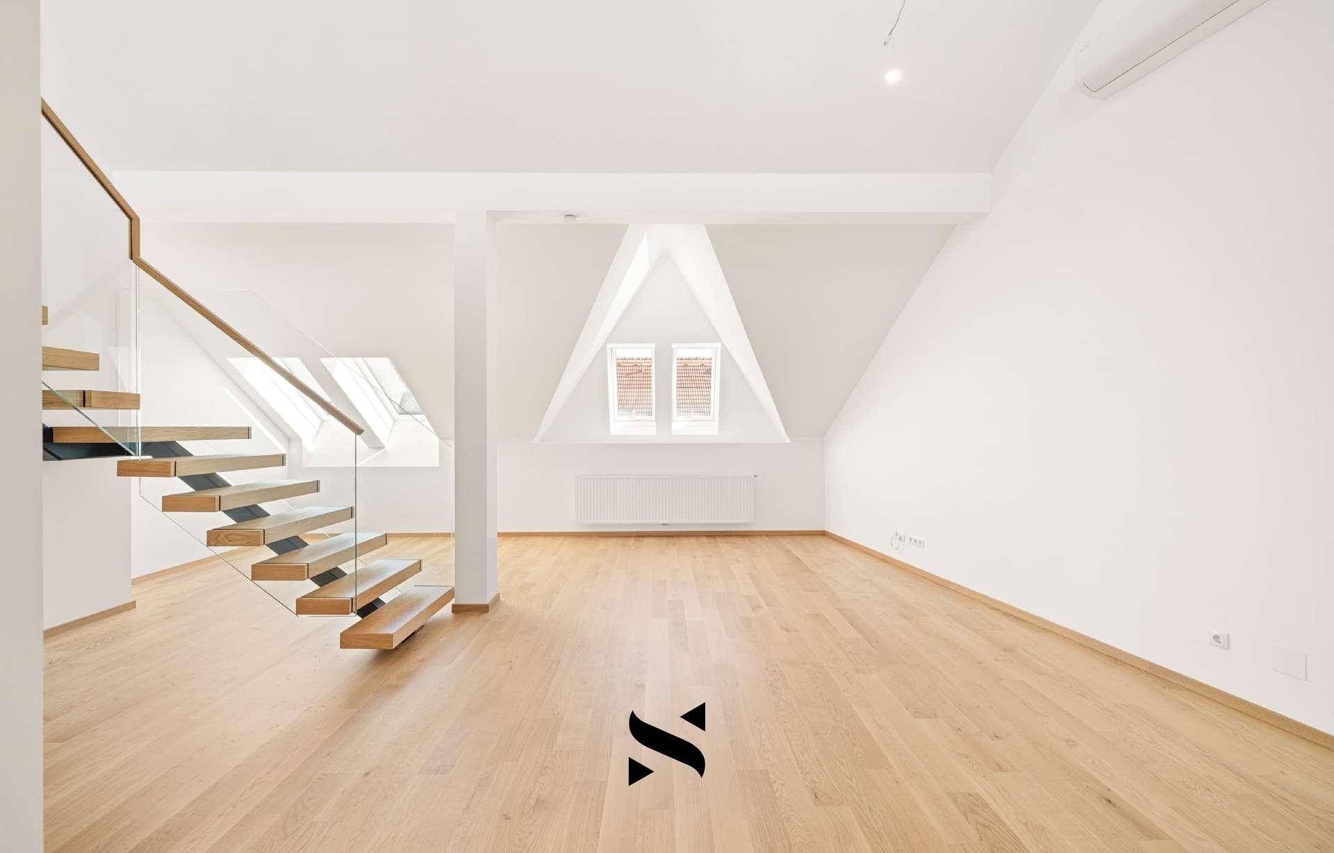Heller Wohnraum mit Holzparkett, Dachschrägen und einem markanten Giebelfenster.