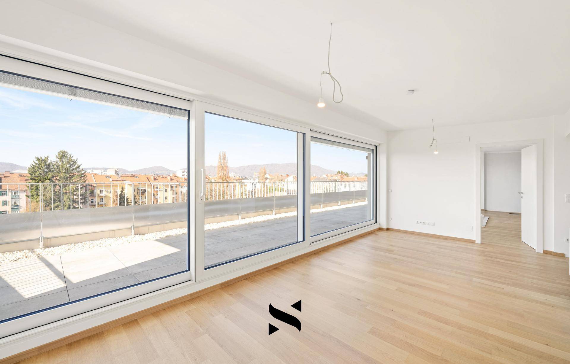 Lichtdurchfluteter Wohnraum mit Parkettboden und breiter Fensterfront zur Dachterrasse.