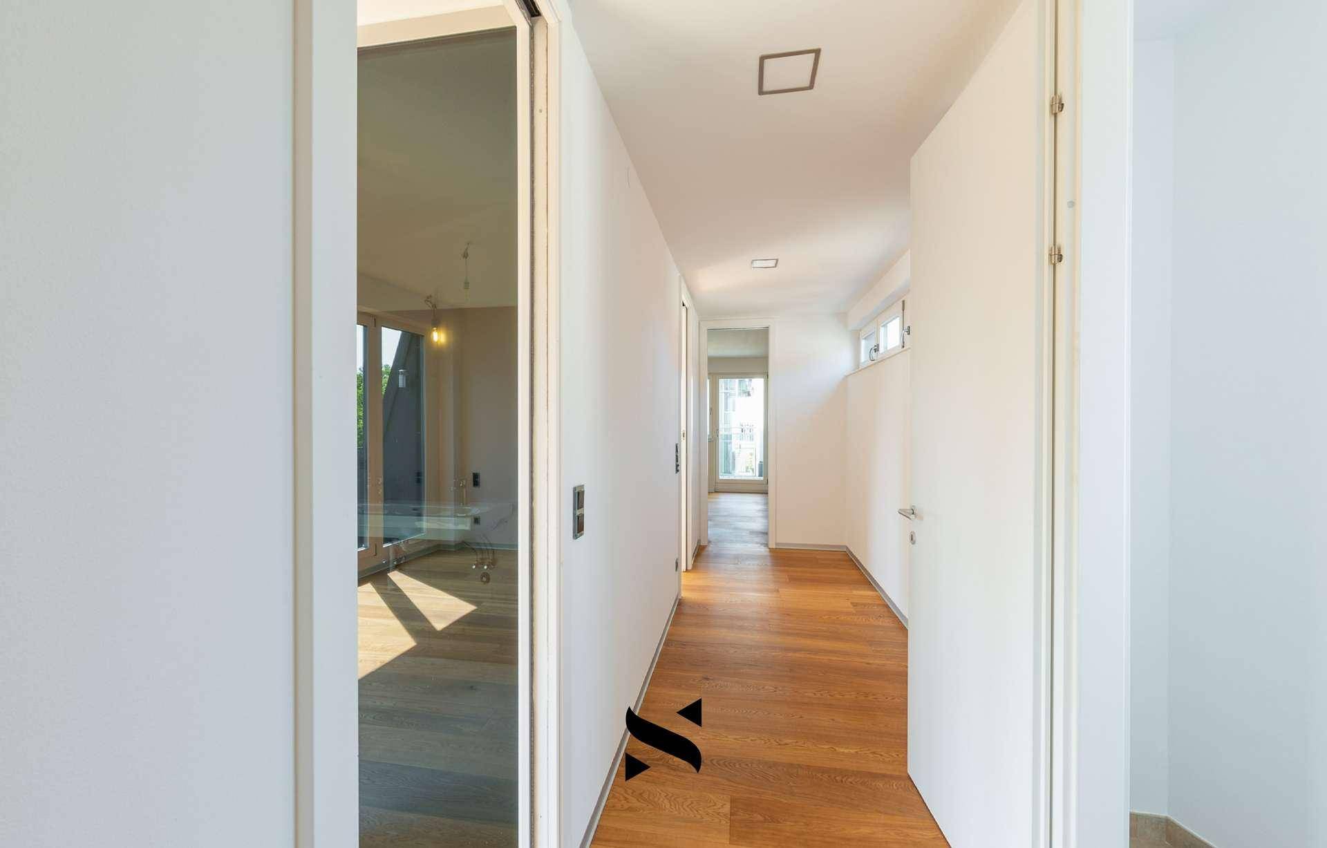 Heller Flur mit Holzboden und modernen Schiebetüren aus Glas.