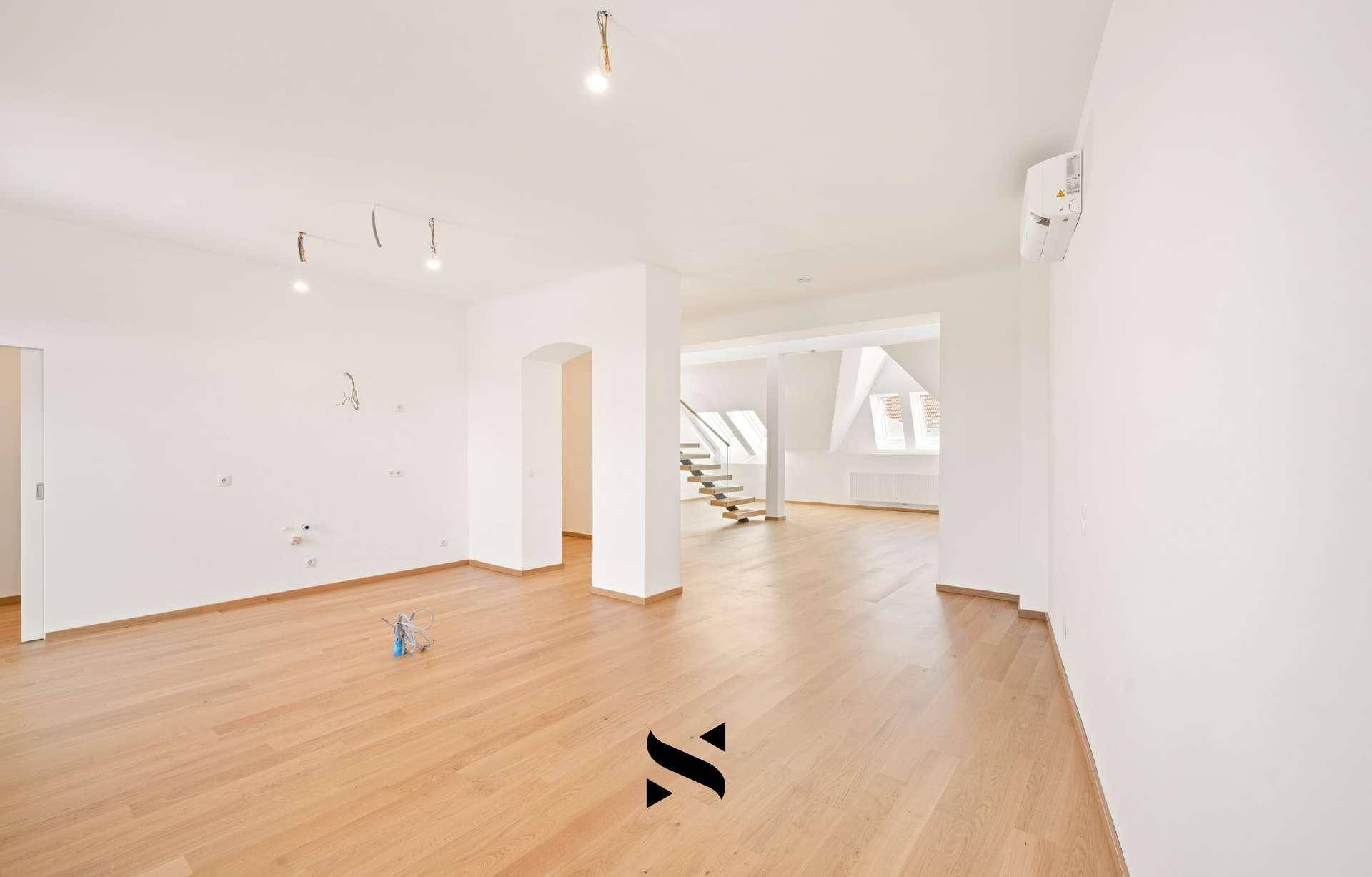 Offener Wohnbereich mit Holzparkettboden, weißen Wänden und Blick auf die Treppe.