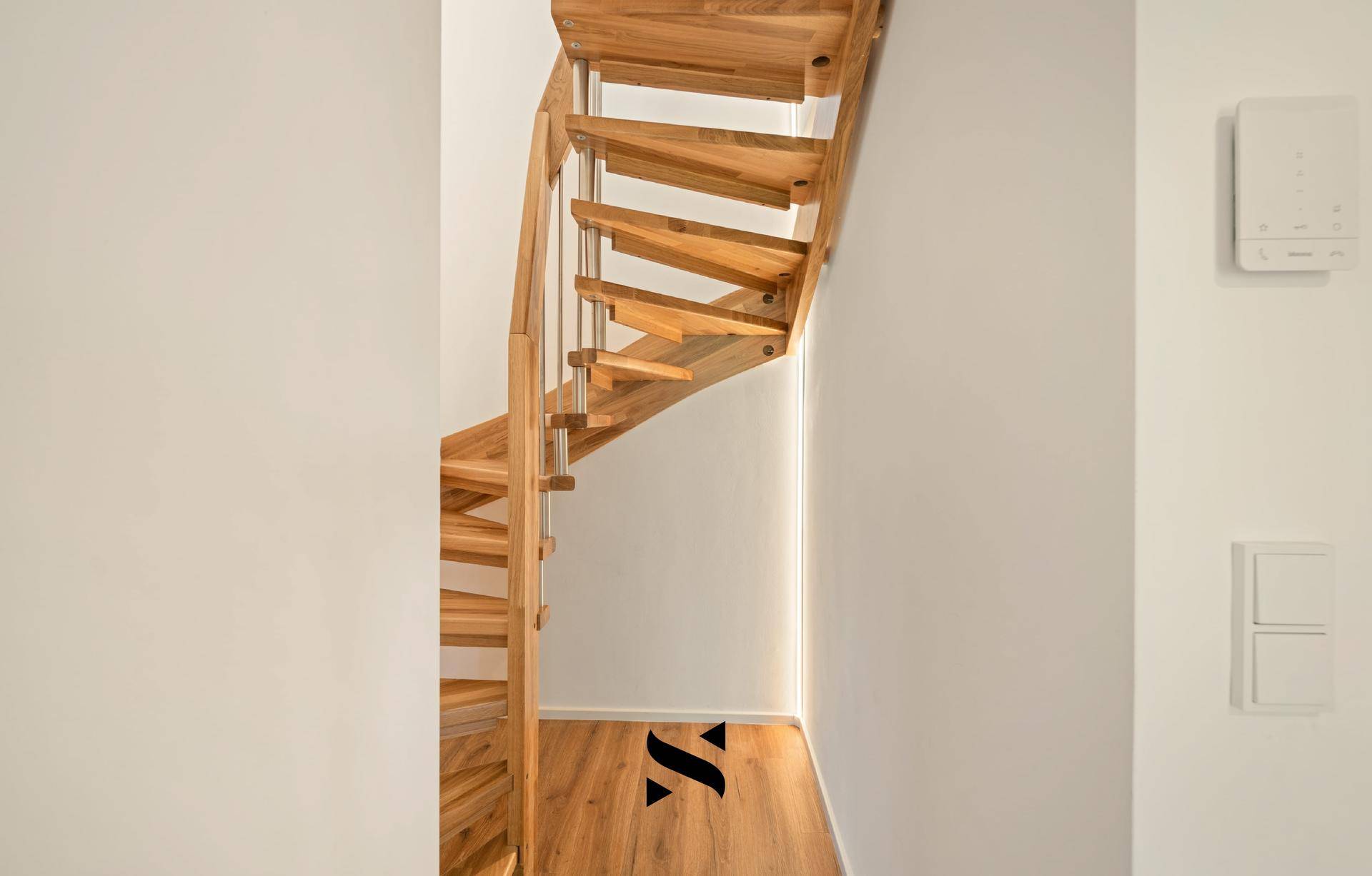 Elegante Holztreppe mit Metallgeländer, die die verschiedenen Ebenen des Hauses verbindet.