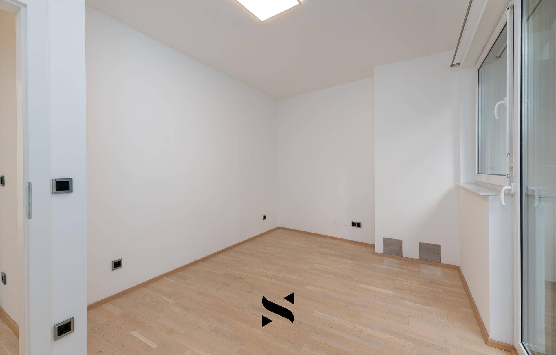 Helles, leeres Zimmer mit Parkettboden und einem Fenster, bereit zur individuellen Gestaltung.