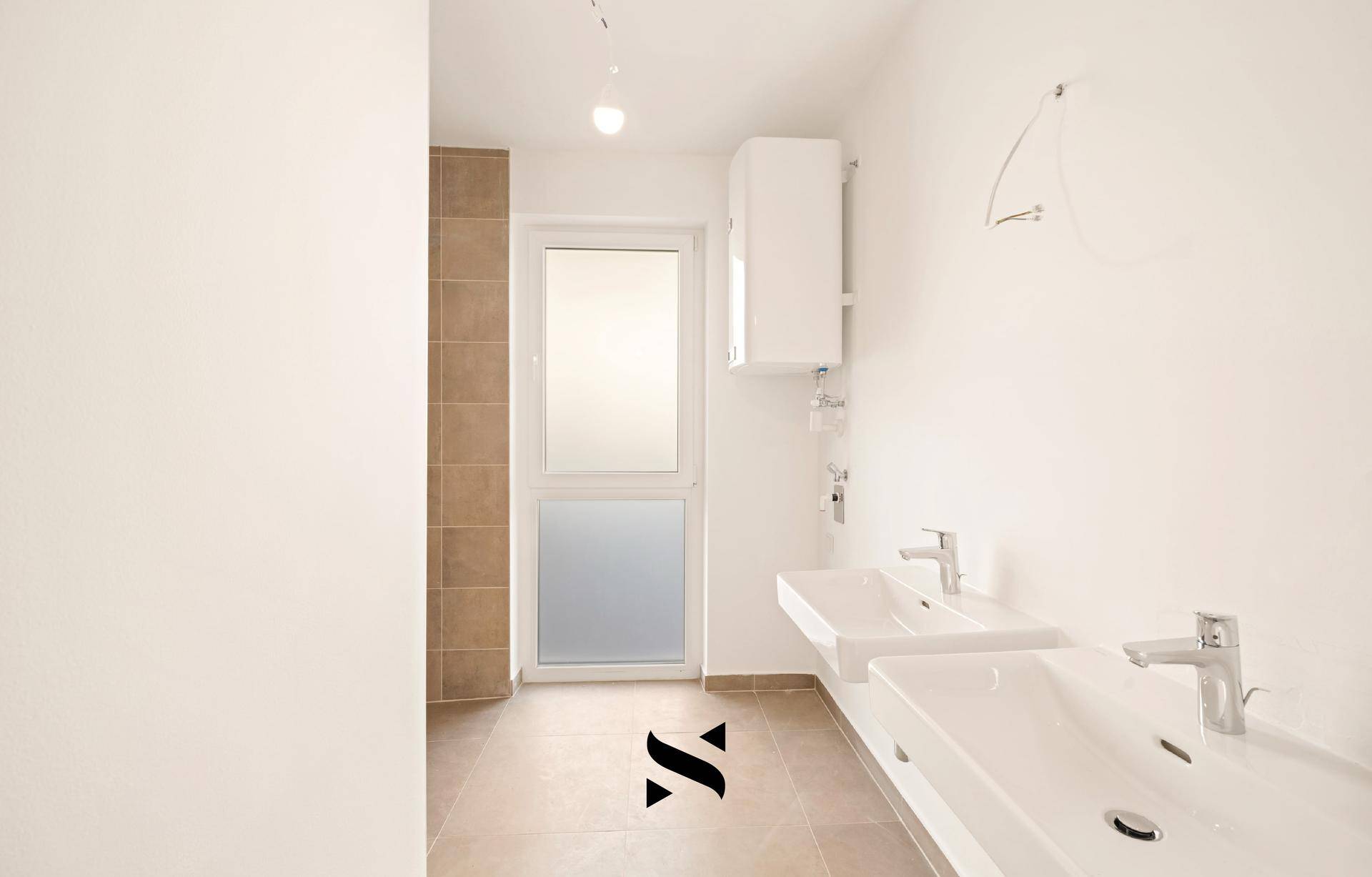 Modernes Badezimmer mit zwei Waschbecken, Fliesenboden und Fenster für Tageslicht.
